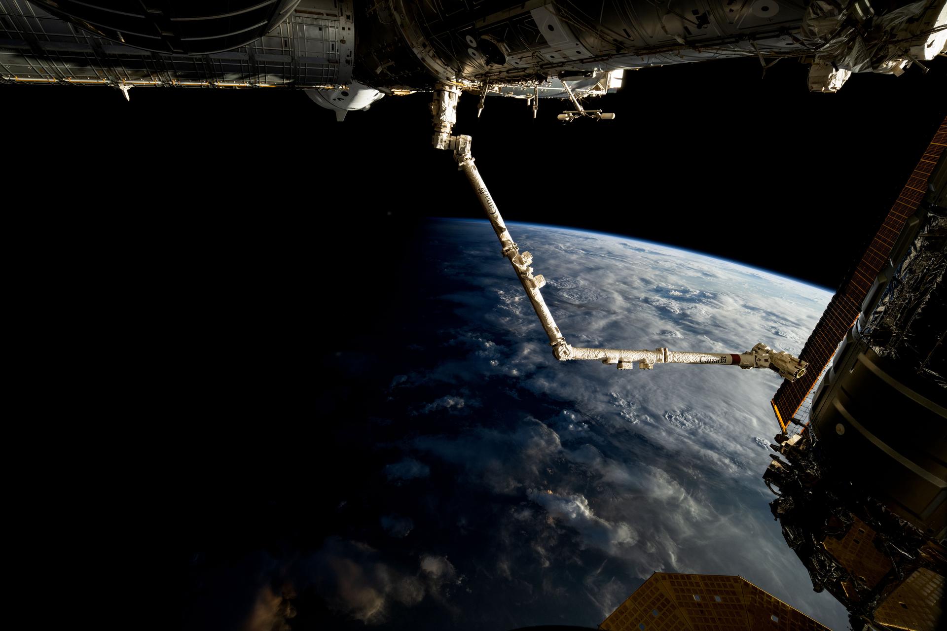 The 57.7-foot-long Candarm2 robotic arm extends from the Harmony module as the International Space Station orbits above the terminator, the line that separates Earth's daytime from nighttime, 261 miles above the African nation of Sudan. Obscured behind Harmony toward upper left, is the SpaceX Dragon Freedom spacecraft.
