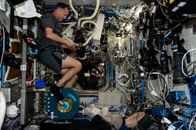 NASA image: Astronaut Nick Hague pedals on an exercise cycle