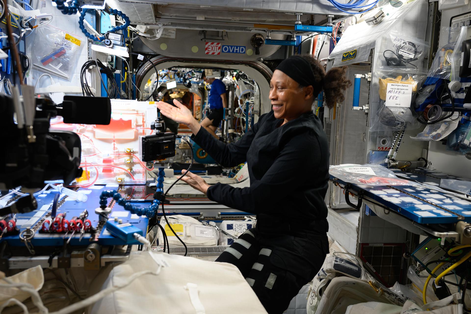 NASA astronaut and Expedition 72 Flight Engineer Jeanette Epps is pictured inside the International Space Station's Harmony module showing off hardware that demonstrates techniques to water plants in the microgravity environment for the Plant Water Management 5 space botany investigation.