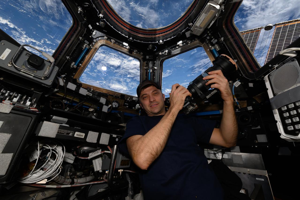 iss072e035858 (Oct. 11, 2024) --- NASA astronaut and Expedition 72 Flight Engineer Matthew Dominick poses for a portrait in the cupola with his camera as the International Space Station orbited 261 miles above the Atlantic Ocean off the coast of Africa.