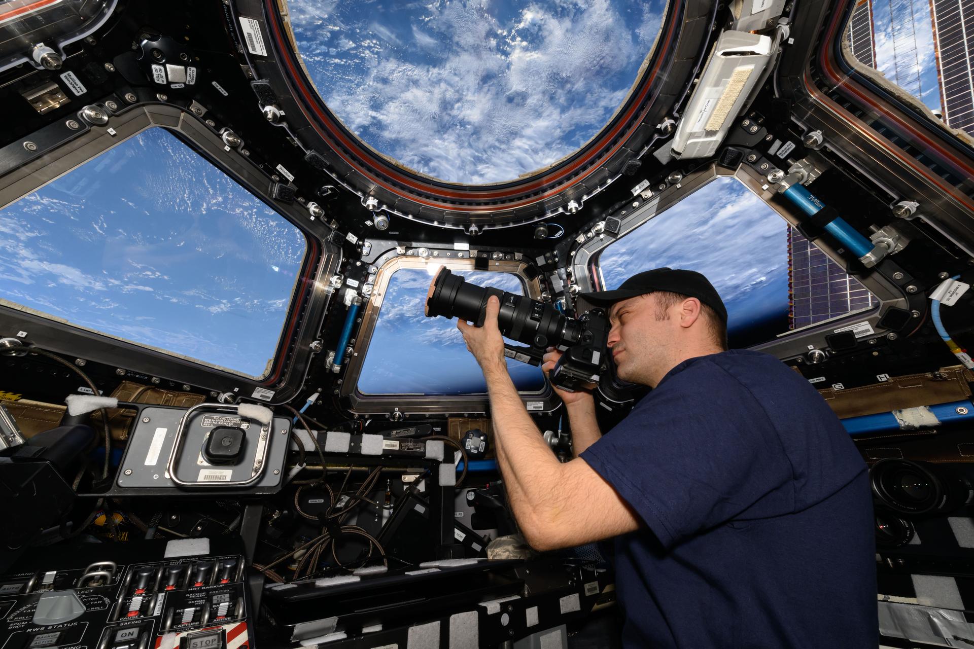 NASA astronaut and Expedition 72 Flight Engineer Matthew Dominick points his camera out a window on the cupola as the International Space Station orbited 262 miles above the Atlantic Ocean off the coast of Africa.