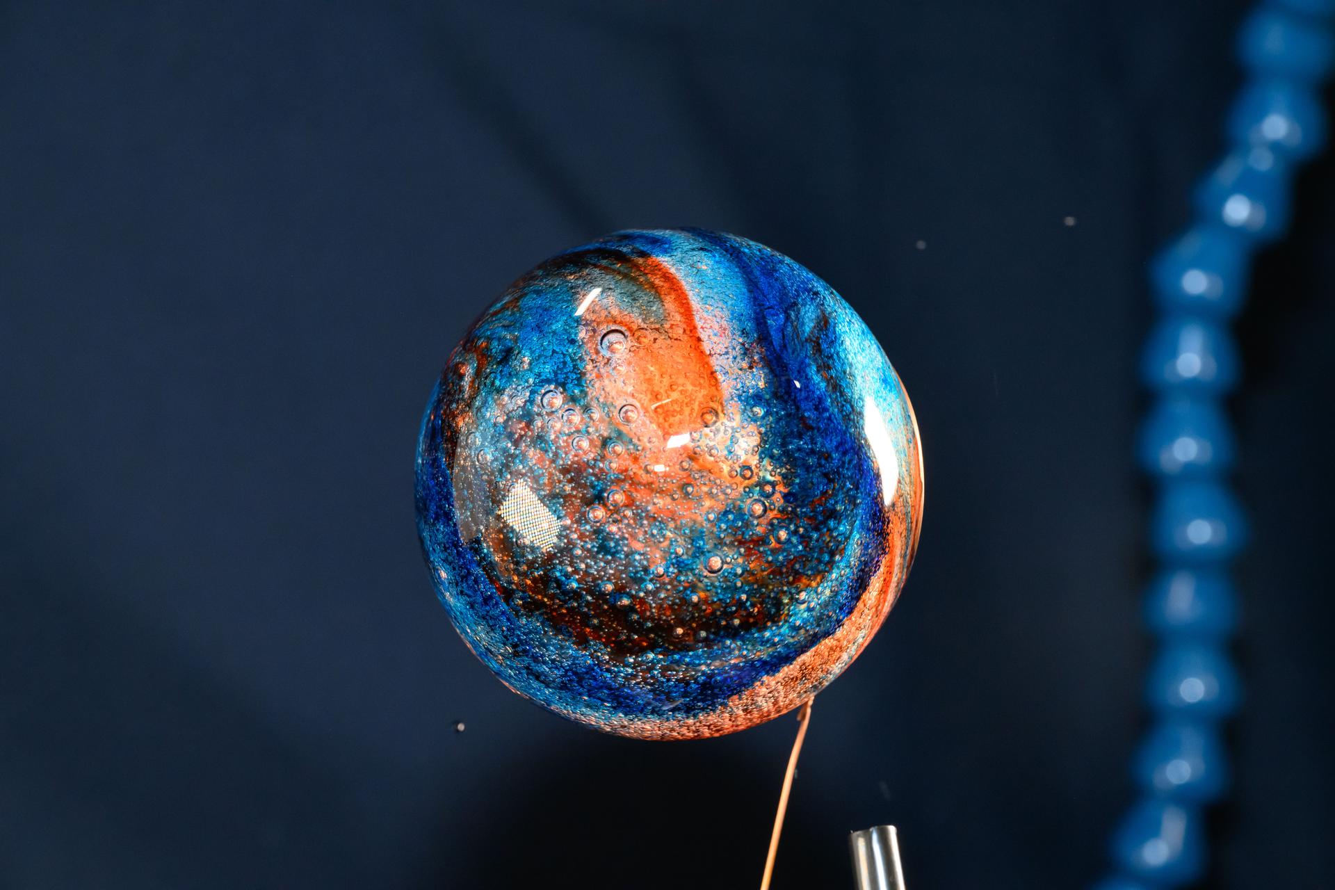 iss072e069593 (Oct. 19, 2024) Science doesn’t always have to be serious on the International Space Station. NASA astronaut Don Pettit has a little fun in microgravity, adding food coloring to a bubble of water to create a miniature Jupiter. Credit: NASA ALT Text: A spherical drop of water with swirls of orange and blue food coloring looks like a tiny planet floating aboard the space station.