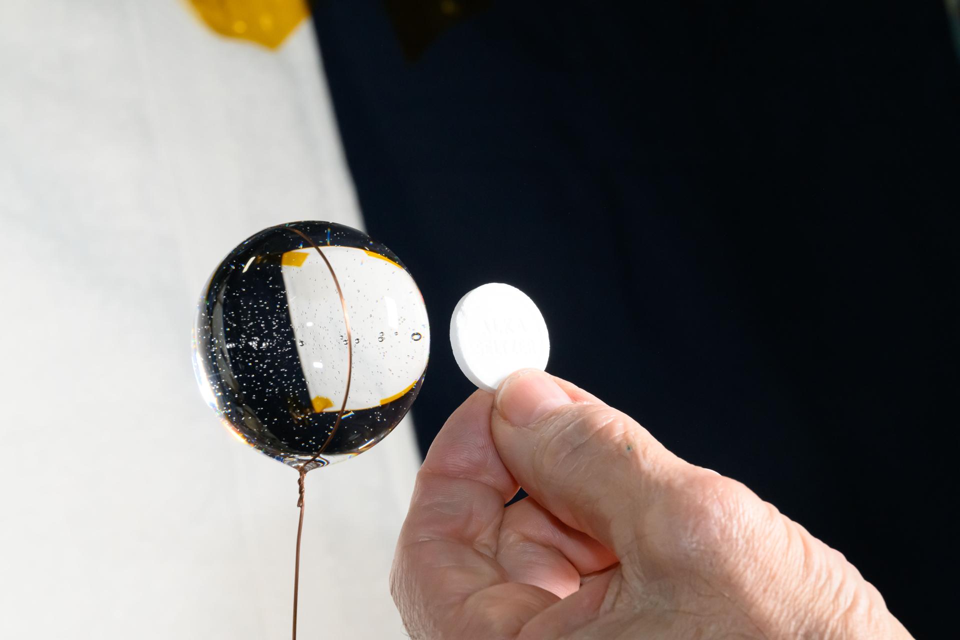An antacid pill is displayed in the hand of NASA astronaut and Expedition 72 Flight Engineer Don Pettit before being placed inside a sphere of water in the microgravity environment of the International Space Station.