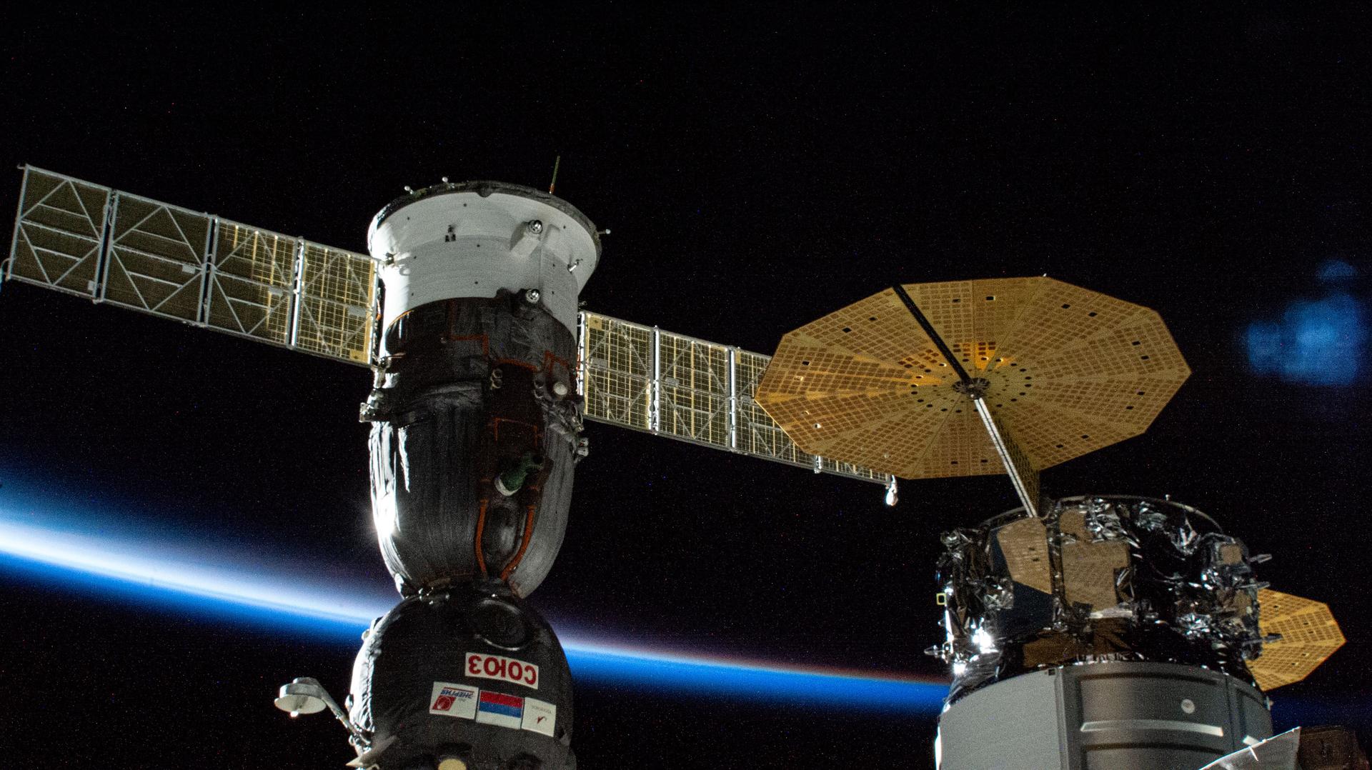Two spacecraft (from left), the Soyuz MS-26 crew ship and the Northrop Grumman Cygnus cargo spacecraft, are pictured attached to the International Space Station while soaring into an orbital sunset 273 miles above the Pacific Ocean south of New Zealand.