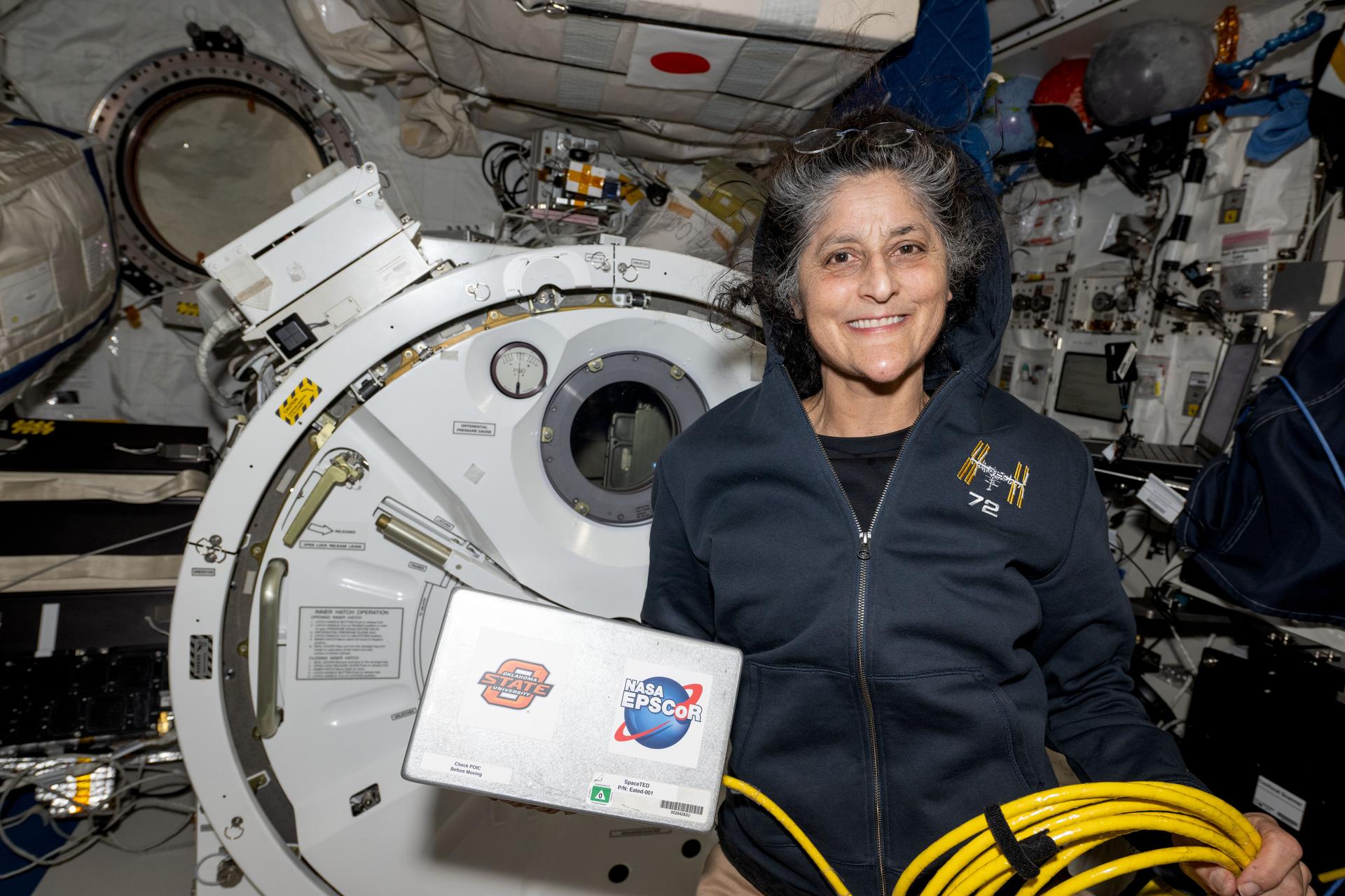 NASA astronaut and Expedition 72 Commander Suni Williams displays the Space Tissue Equivalent Dosimeter (SpaceTED) hardware inside the International Space Station's Kibo laboratory module. SpaceTED is a technology demonstration that can measure radiation dosages and characterize the radiaton environment in microgravity to protect crew members and spacecraft hardware.