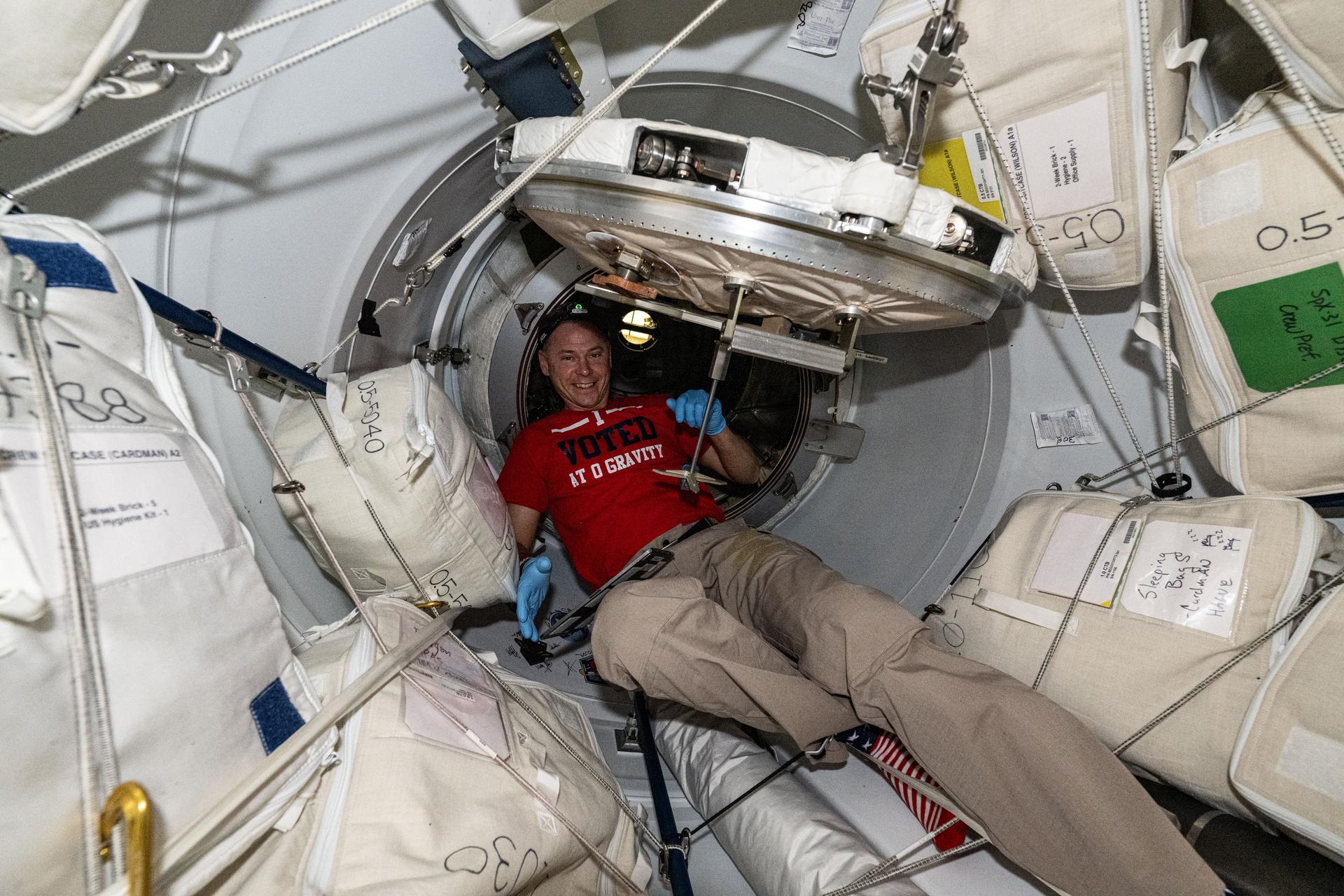 NASA astronaut and Expedition 72 Flight Engineer Nick Hague is pictured in the vestibule between the International Space Station's forward port on the Harmony module and the SpaceX Dragon cargo spacecraft. Dragon had automatically docked to the orbital outpost less than hour before this photograph was taken and its hatch had not been opened yet.960A1038.NEF