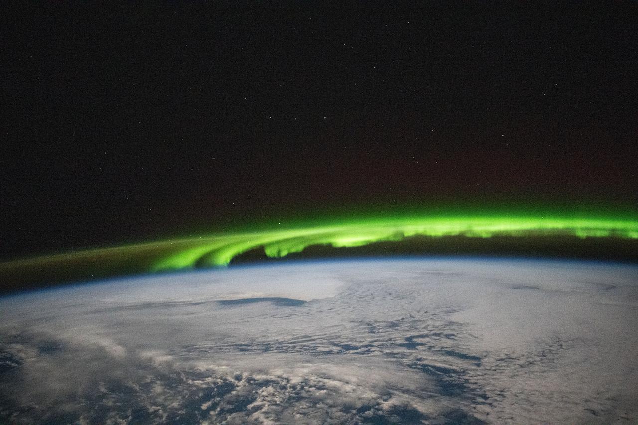 iss072e188141 (Nov. 15, 2024) --- A bright green aurora borealis streams above Earth's surface as the International Space Station orbited 269 miles above a cloudy North Pacific Ocean south of Alaska's Aleutian Islands.