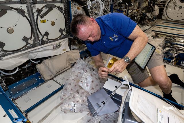 NASA image: Astronaut Butch Wilmore swaps sample cassettes inside the Advanced Space Experiment Processor-4
