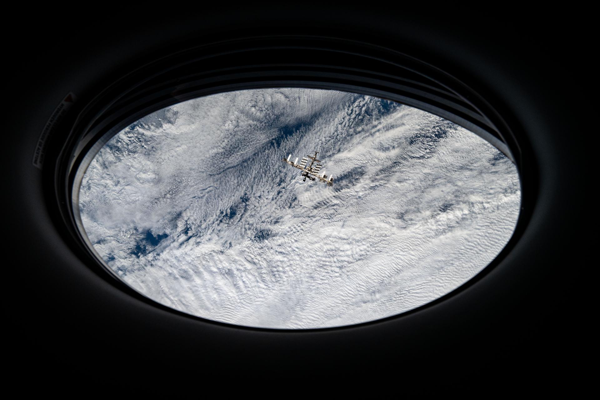 The International Space Station is pictured from a window on the SpaceX Dragon crew spacecraft by a SpaceX Crew-8 member shortly after undocking from the Harmony module's space-facing port. The orbital outpost was soaring 272 miles above a cloudy Pacific Ocean off the coast of Chile at the time of this photograph.