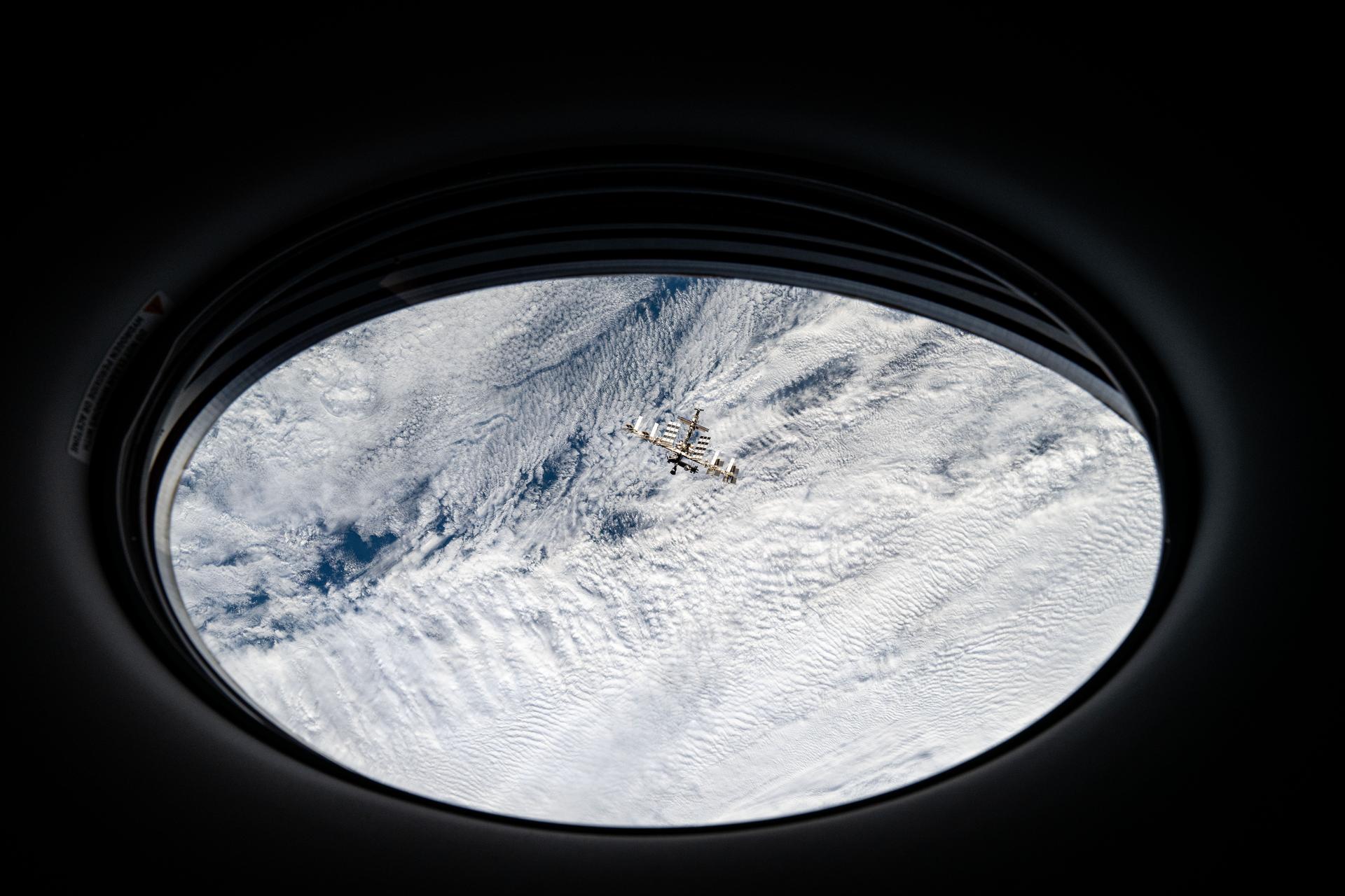 The International Space Station is pictured from a window on the SpaceX Dragon crew spacecraft by a SpaceX Crew-8 member shortly after undocking from the Harmony module's space-facing port. The orbital outpost was soaring 272 miles above a cloudy Pacific Ocean off the coast of Chile at the time of this photograph.