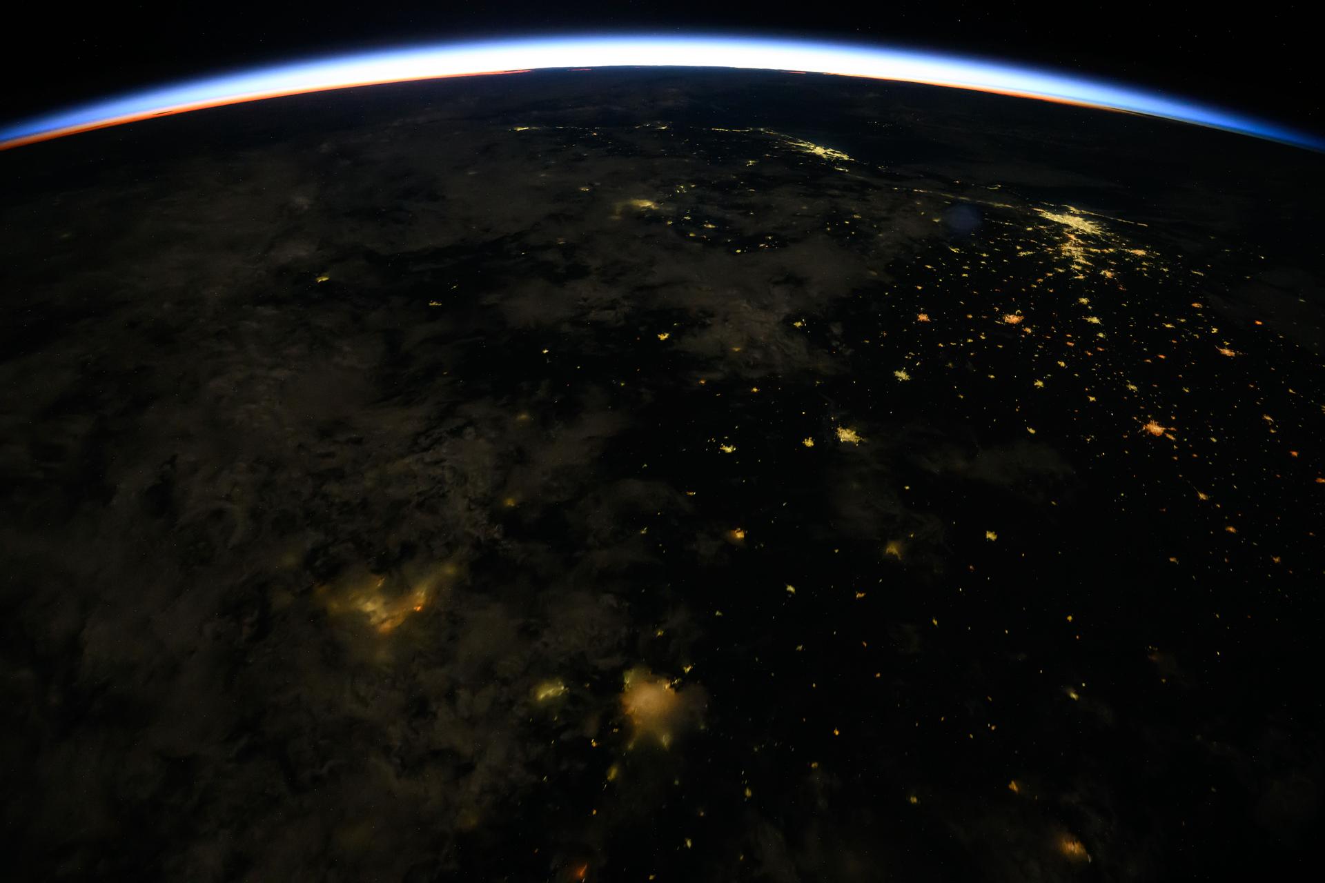 An orbital sunrise crowns Earth's horizon in this photograph from the International Space Station as it orbited 261 miles above Brazil. At top right, the city lights of Rio de Janiero and Sao Paulo on the Atlantic coast are visible from the orbital outpost.