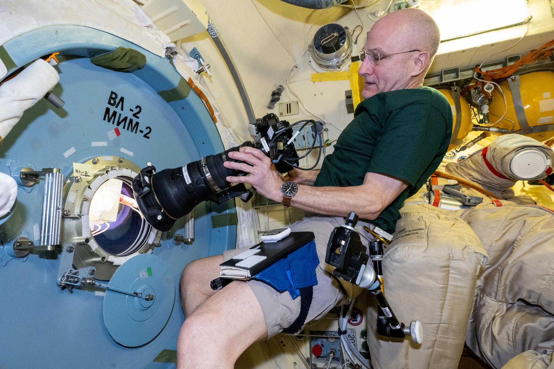 NASA astronaut and Expedition 72 Flight Engineer Don Pettit points a camera outside a window on the International Space Station's Poisk module for a sun photography session.