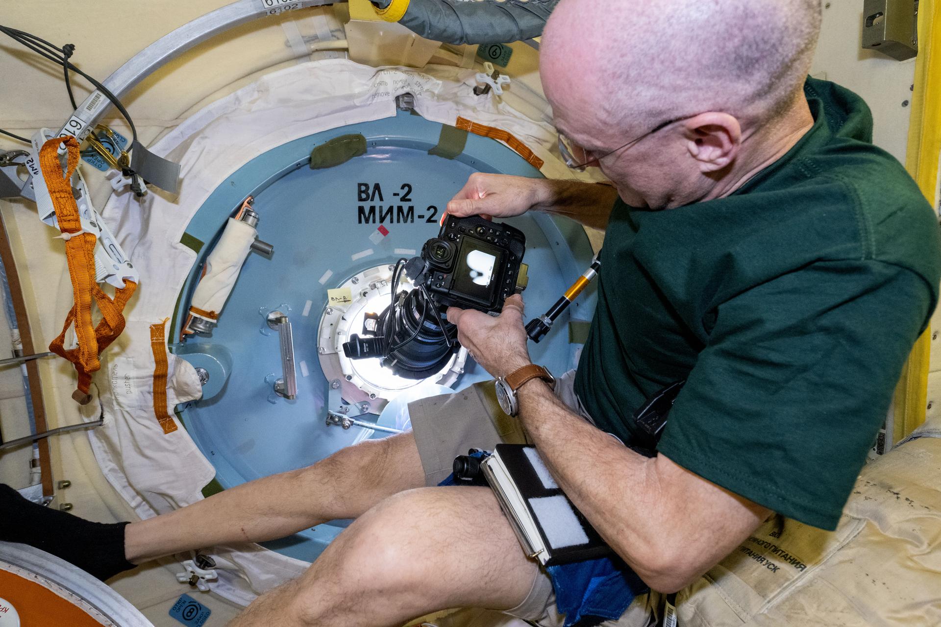 NASA astronaut and Expedition 72 Flight Engineer Don Pettit points a camera outside a window on the International Space Station's Poisk module for a sun photography session.