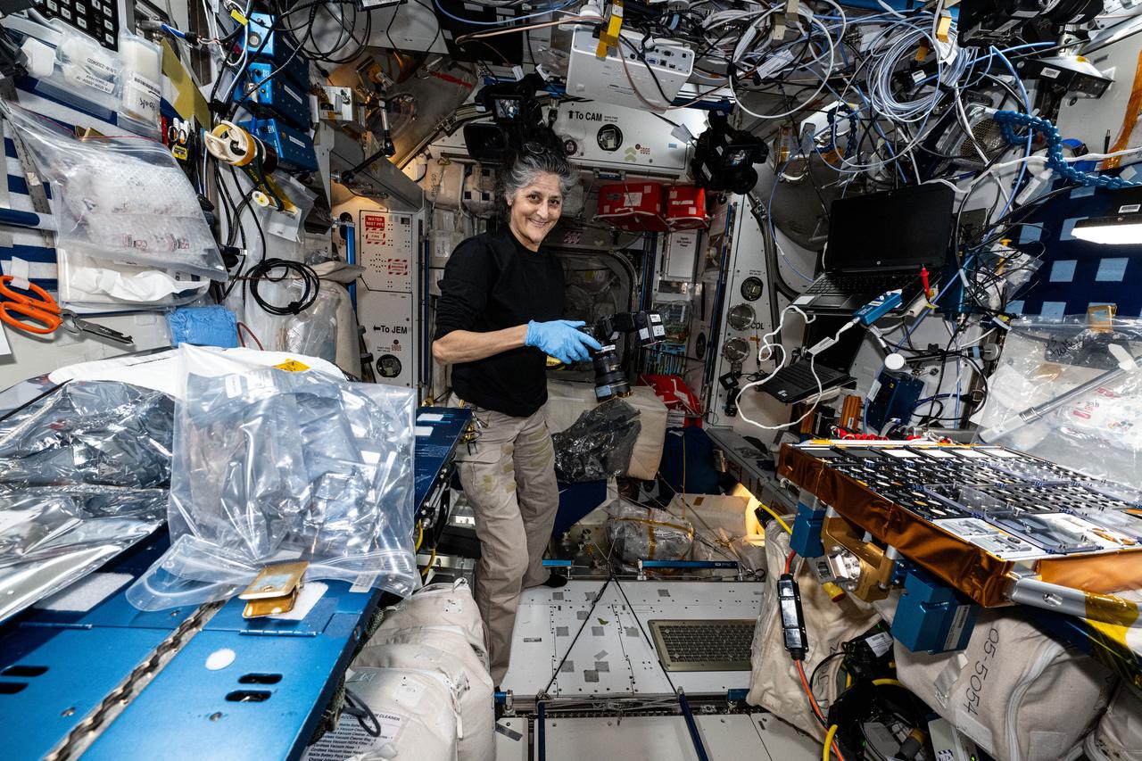 iss072e363105 (Dec. 13, 2024) --- NASA astronaut and Expedition 72 Commander Suni Williams photographs the European Materials Ageing (EMA) experiment hardware beng set up inside the International Space Station's Harmony module. EMA contains a variety of samples that will be exposed to the space environment to learn how to improve the development of space hardware and applications for missions to the Moon, Mars, and beyond. The external investigation will operate outside the Columbus laboratory module for about a year.