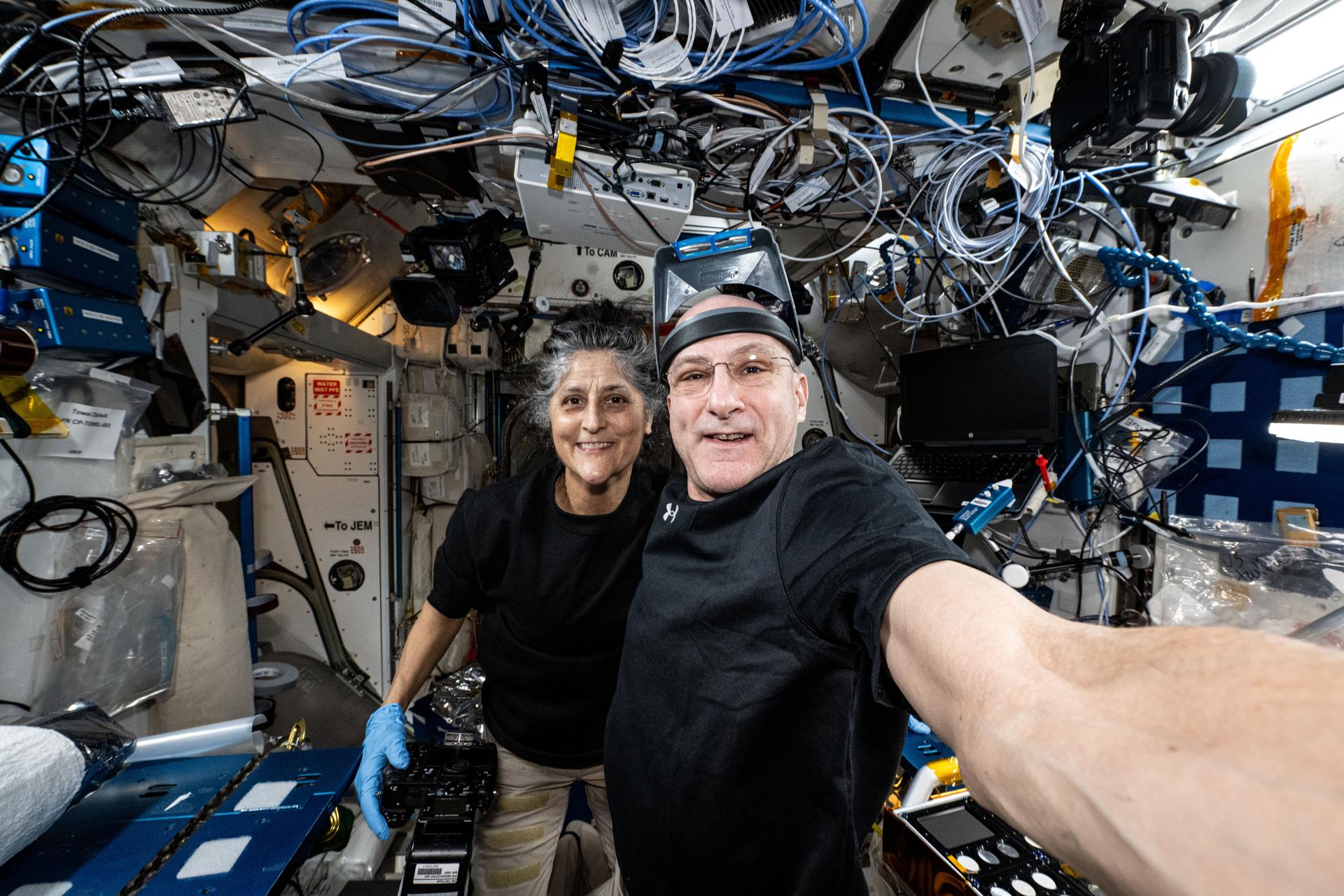 NASA astronauts Suni Williams and Don Pettit, Expedition 72 Commander and Flight Engineer respectively, take a break from science maintenance activities and pose for a selfie-portrait aboard the International Space Station's Harmony module.