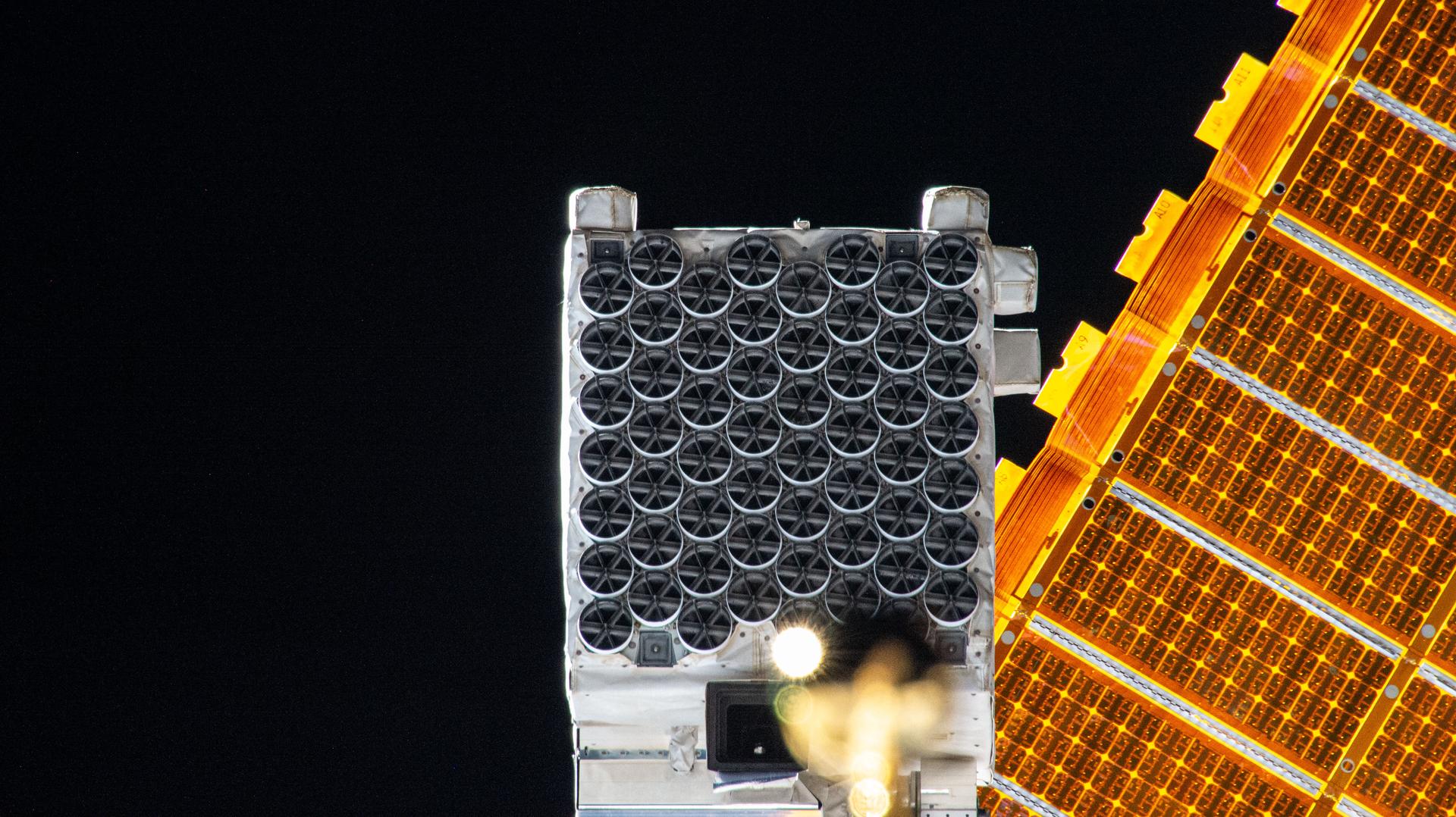 The NICER (Neutron star Interior Composition Explorer) X-ray telescope is pictured installed on the starboard side of the International Space Station's integrated truss segment. NICER's 56 X-ray concentrators are covered by thermal shields, or filters, that block ultraviolet, infrared, and visible light while allowing X-rays to pass through to the mirrors underneath enabling the observation of neutron stars. Several thermal shields have been damaged allowing unwanted sunlight to "leak" into the astrophysics instrument interfering with X-ray measurements. NASA astronauts Nick Hague and Sun Williams will conduct a spacewalk on Jan. 16 to patch the damaged thermal shields and restore NICER for daytime scientific operations.