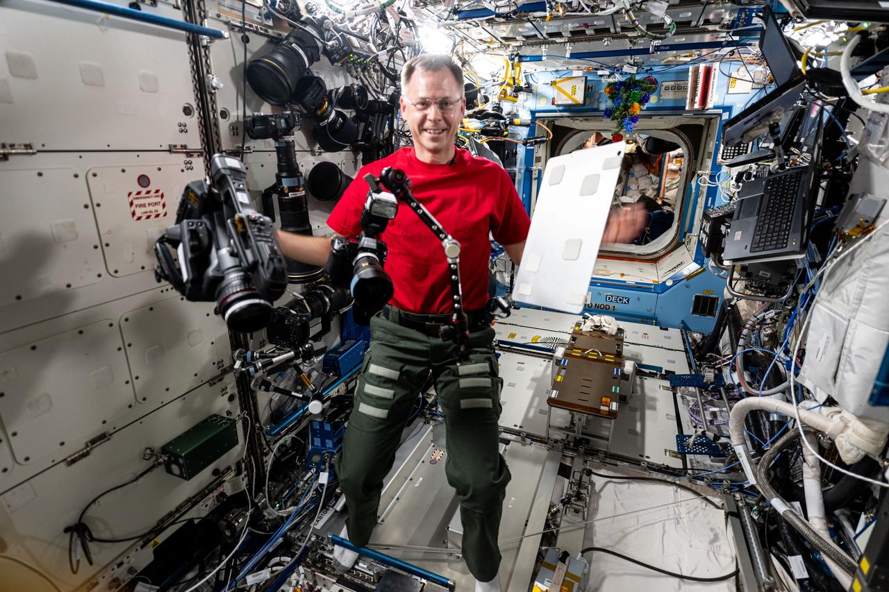 iss072e391353 (Dec. 17, 2024) --- NASA astronaut and Expedition 72 Flight Engineer Nick Hague demonstrates the range of motion and stability of student-designed space hardware aboard the International Space Station's Destiny laboratory module. Hague was testing the HUNCH (High school students United with NASA to Create Hardware) Utility Bracket for its ability to hold and position cameras, computer tablets, and other tools astronauts use daily.