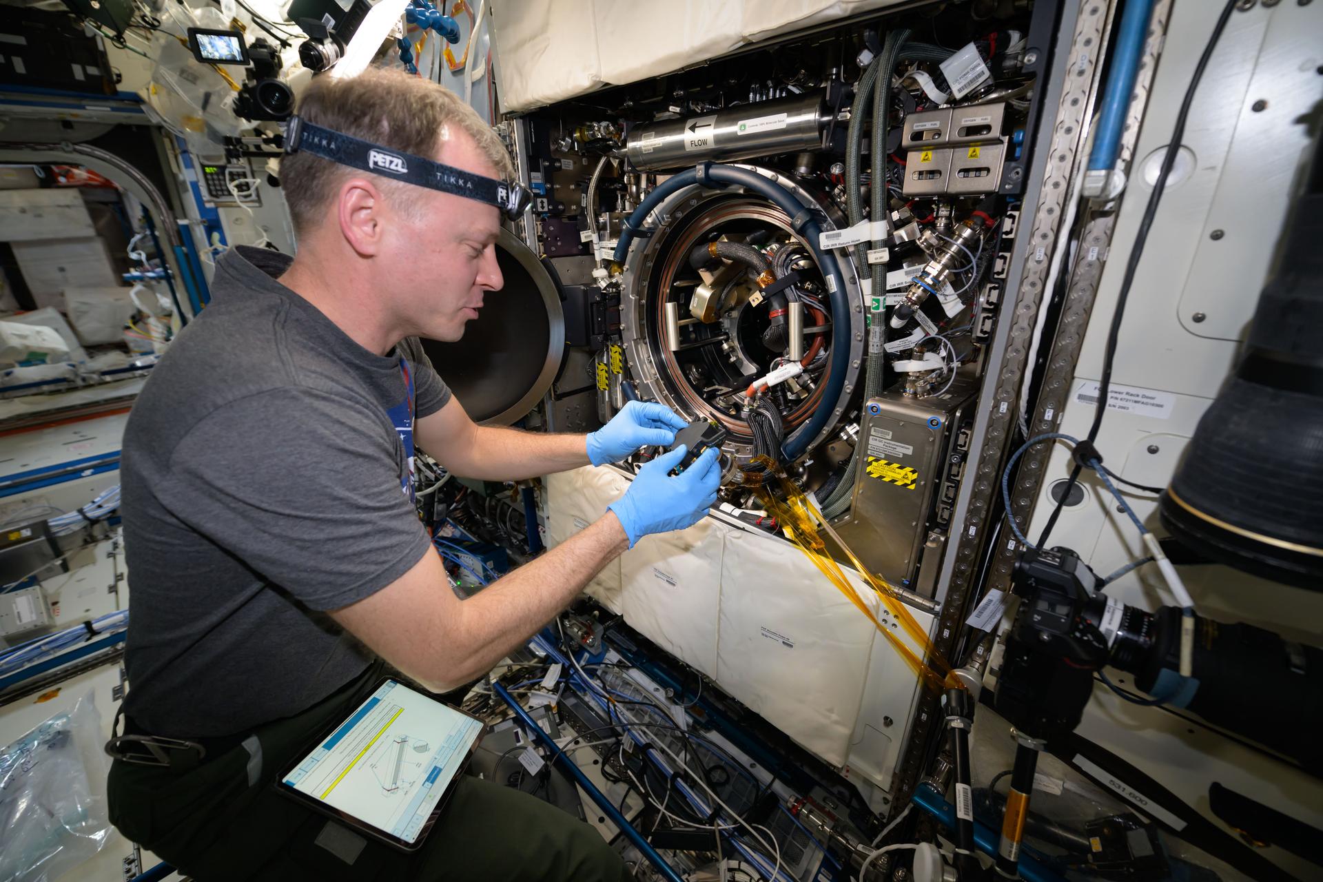 NASA astronaut and Expedition 72 Flight Engineer Nick Hague processes samples inside the Destiny laboratory module's Combustion Integrated Rack. Those samples are being observed for how they burn in weightlessness to learn how to prevent fires on spacecraft.