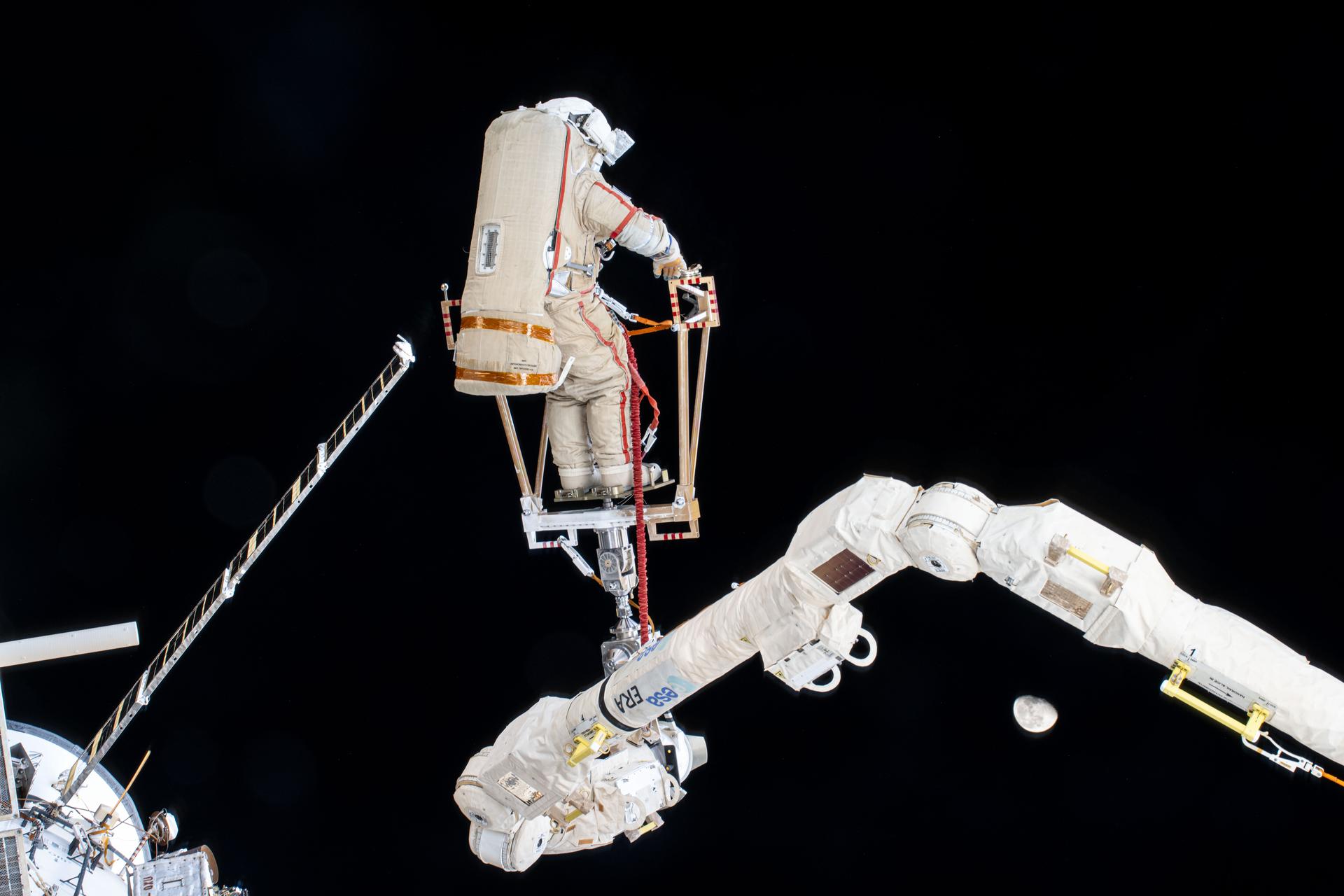 Roscosmos cosmonaut and Expedition 72 Flight Engineer Alexey Ovchinin is maneuvered using the European robotic arm during a seven-hour and 17-minute spacewalk. He and fellow Flight Engineer Ivan Vagner (not pictured) partnered together in the vacuum of space on Dec.19 installing a celestial X-ray experiment and removng other scientific hardware on the exterior of the International Space Station. The waning gibbous Moon is at lower right as the orbital outpost soared 262 miles above the Pacific Ocean.