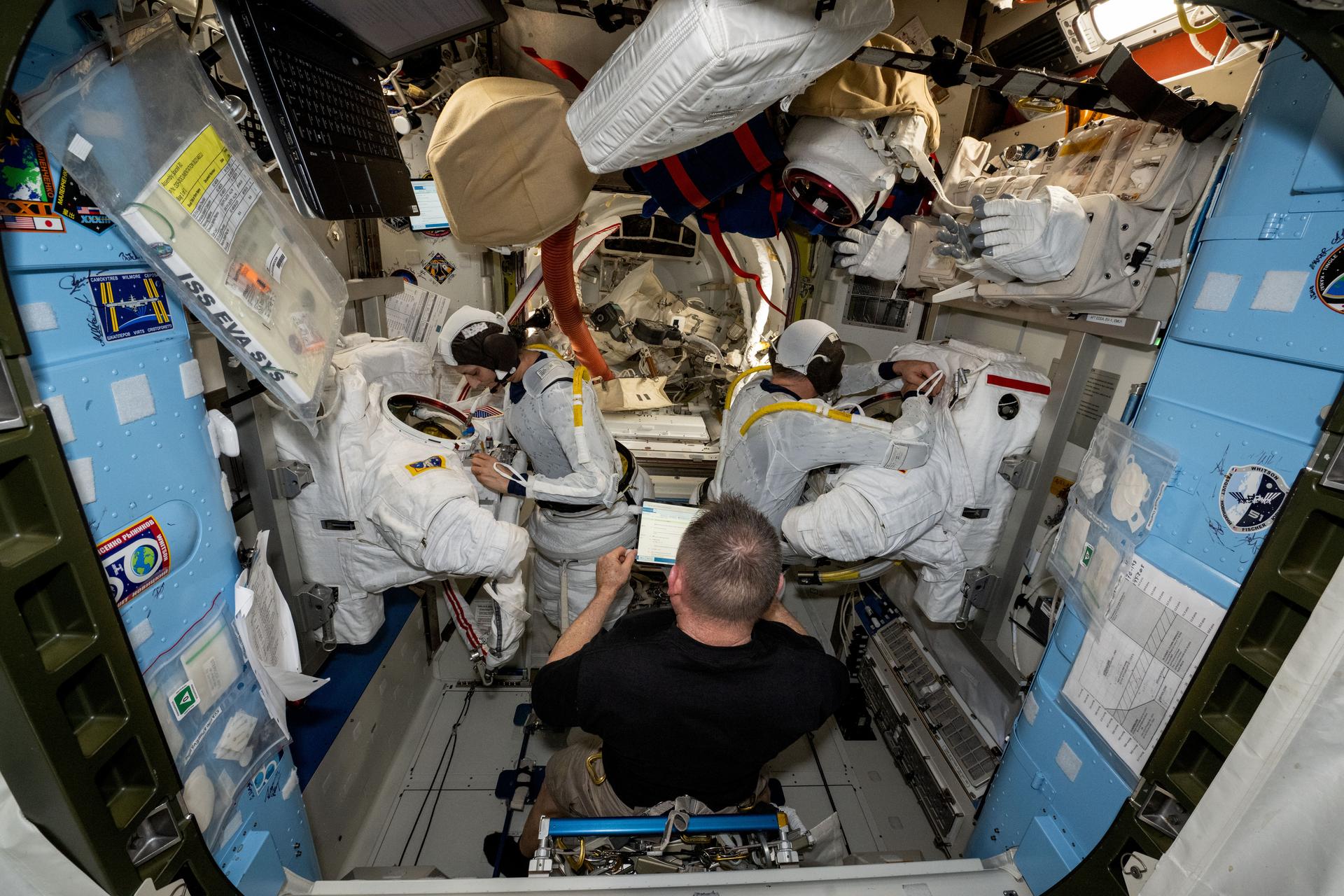 NASA astronaut and Expedition 72 Flight Engineer Butch Wilmore (center) assists International Space Station Commander Suni Williams (left) and Flight Engineer Nick Hague (right), both NASA astronauts, as they prepare to evaluate their spacesuits in a pressurized configuration. Hague and Williams are scheduled to exit the orbital outpost on Jan. 16 for a spacewalk to service astrophysics gear including the NICER X-ray telescope and the Alpha Magnetic Spectrometer.