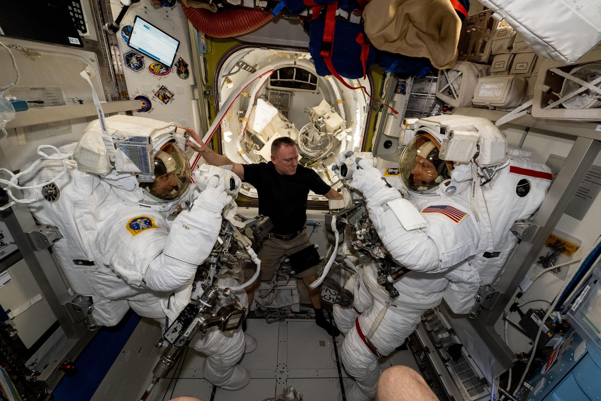NASA astronaut and Expedition 72 Flight Engineer Butch Wilmore (center) assists International Space Station Commander Suni Williams (left) and Flight Engineer Nick Hague (right), both NASA astronauts, as they prepare to evaluate their spacesuits in a pressurized configuration. Hague and Williams are scheduled to exit the orbital outpost on Jan. 16 for a spacewalk to service astrophysics gear including the NICER X-ray telescope and the Alpha Magnetic Spectrometer.