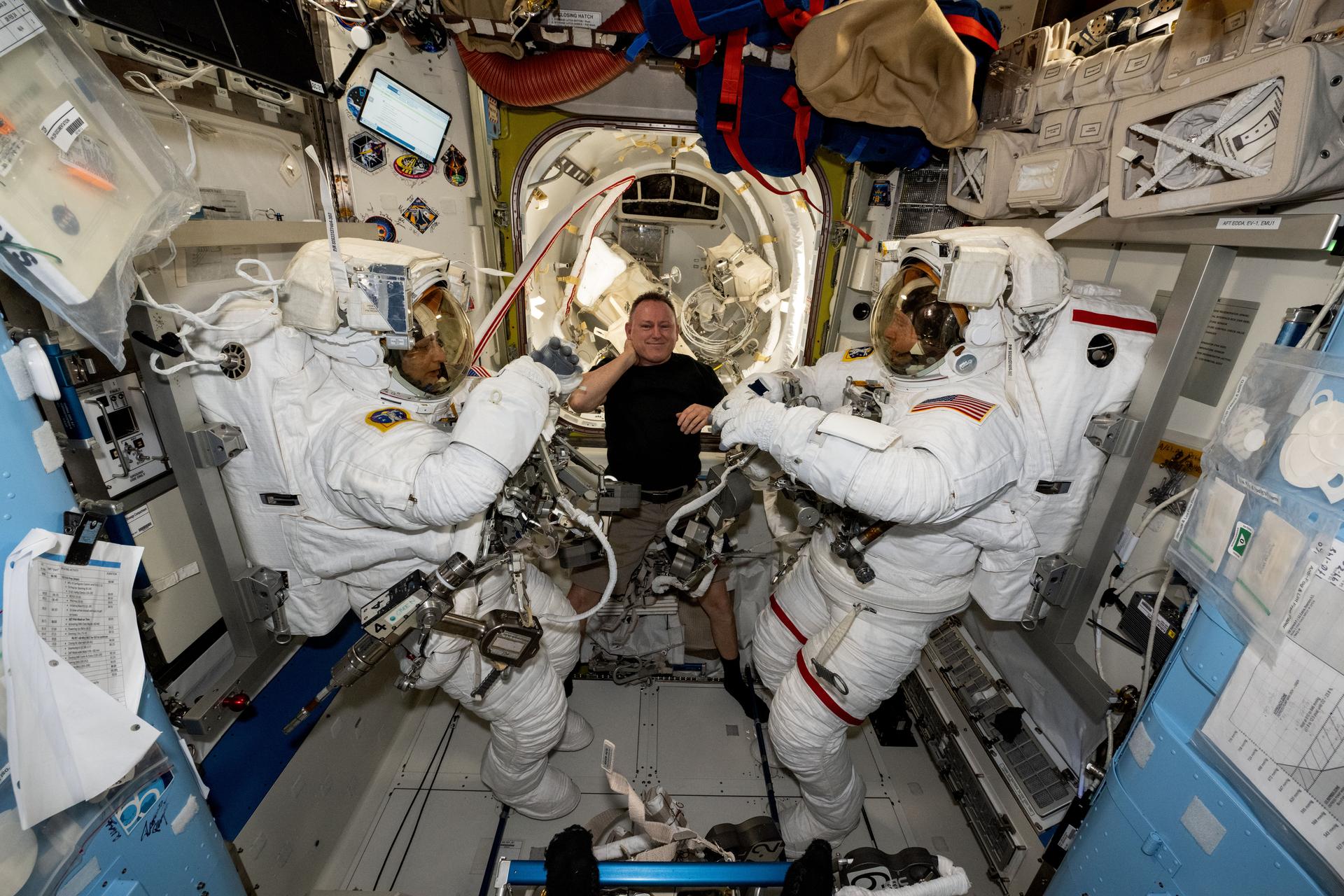 NASA astronaut and Expedition 72 Flight Engineer Butch Wilmore (center) assists International Space Station Commander Suni Williams (left) and Flight Engineer Nick Hague (right), both NASA astronauts, as they prepare to evaluate their spacesuits in a pressurized configuration. Hague and Williams are scheduled to exit the orbital outpost on Jan. 16 for a spacewalk to service astrophysics gear including the NICER X-ray telescope and the Alpha Magnetic Spectrometer.