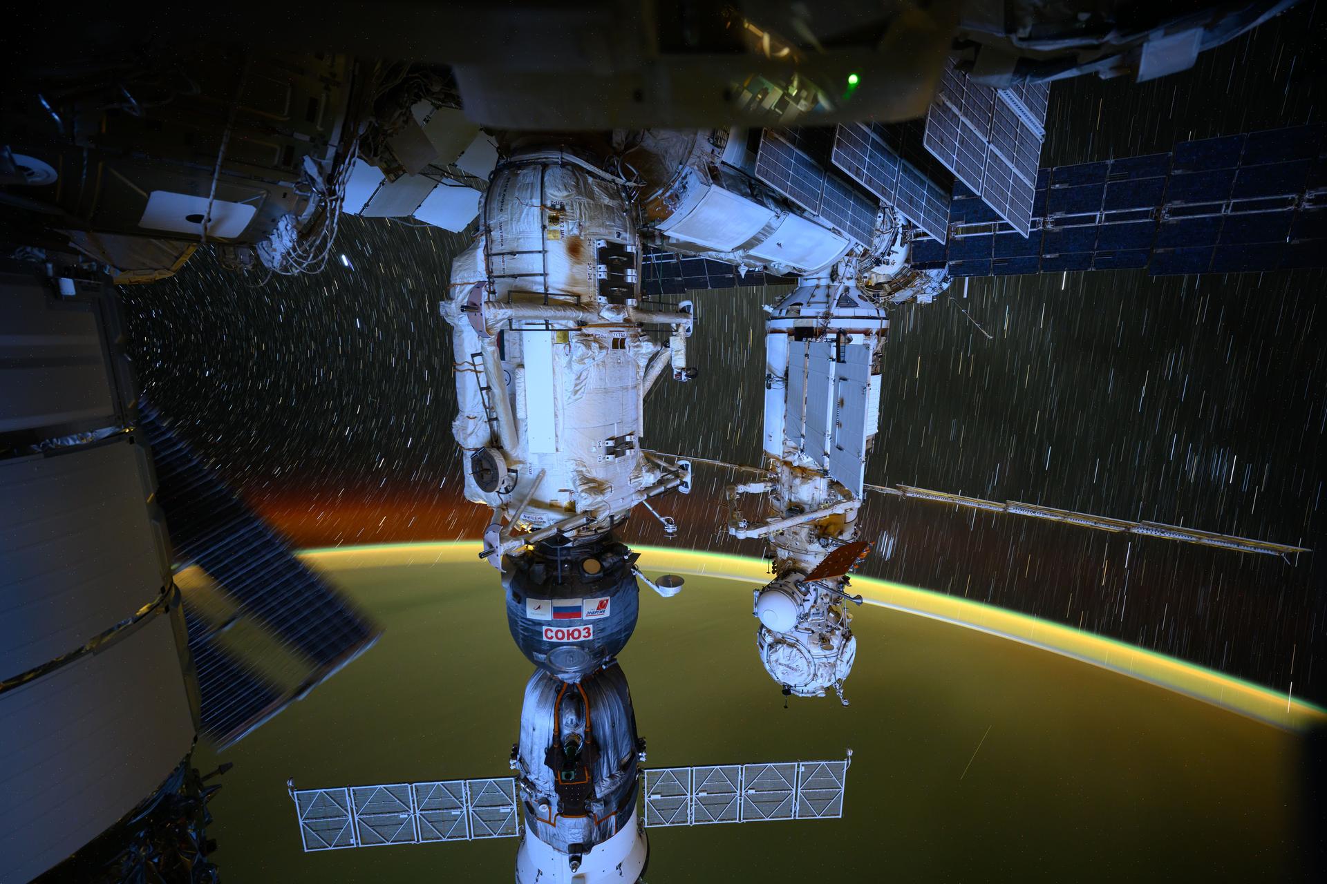 This long-duration photograph highlights the Roscosmos segment of the International Space Station with the Soyuz MS-26 crew ship (bottom center) docked to the Rassvet module. Star trails and Earth's atmospheric glow are also prominently pictured from the orbital outpost as it soared 258 miles above the Pacific Ocean.