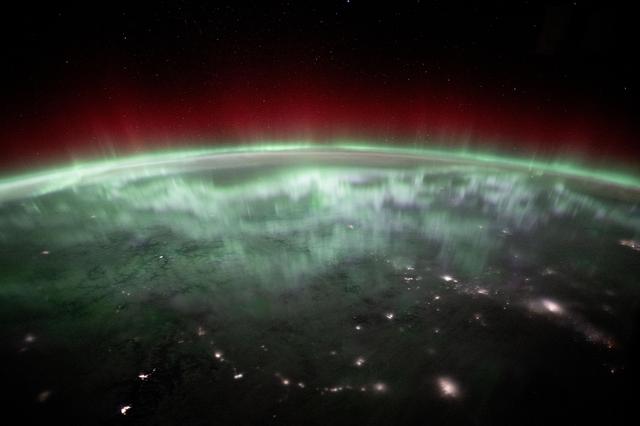 NASA image: An aurora shimmers and dances above the city lights of Canada