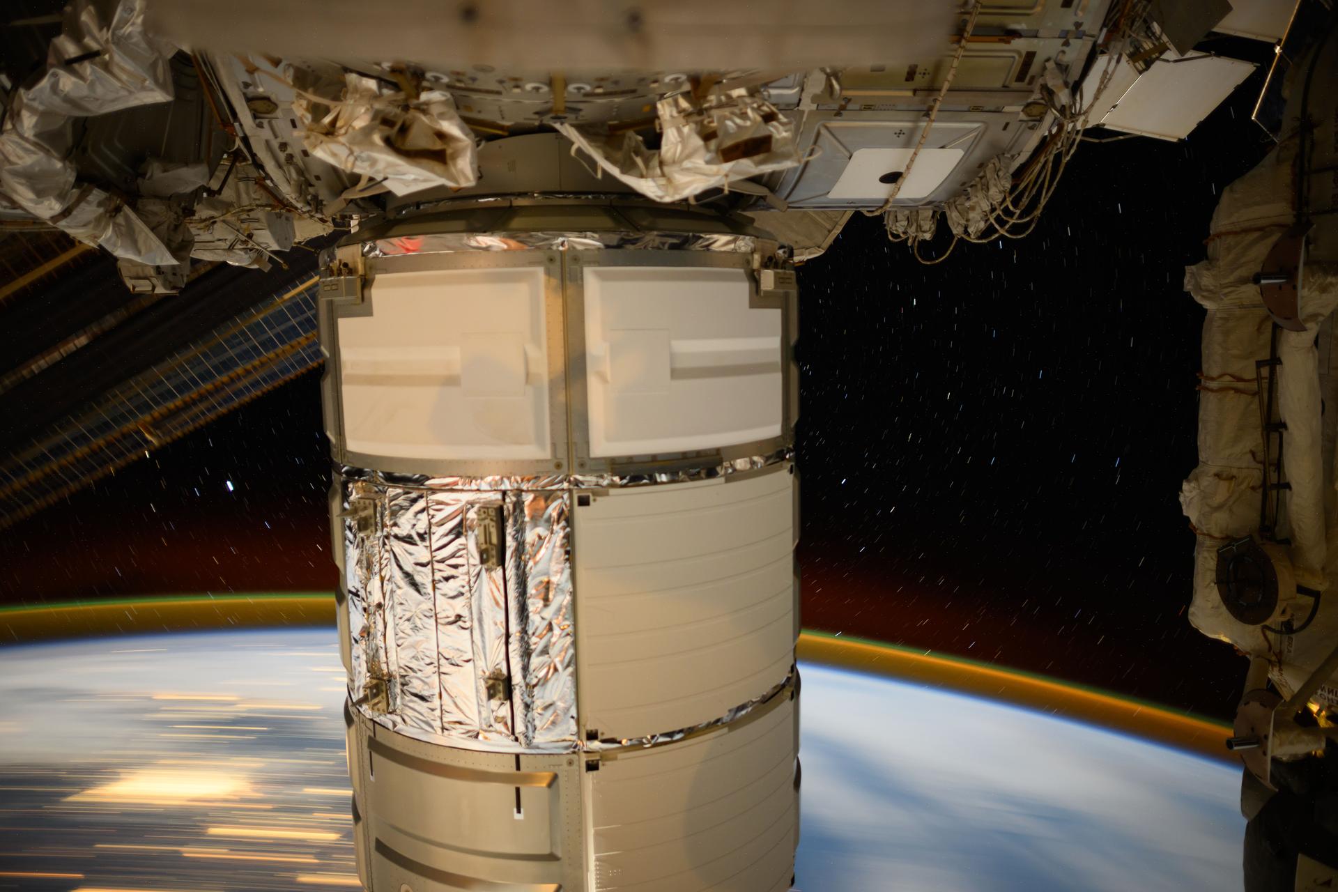 Northrop Grumman's Cygnus space freighter dominates this long-duration photograph with the atmospheric glow blanketing Earth's horizon as the International Space Station orbited 261 miles above the Brittany region of France.