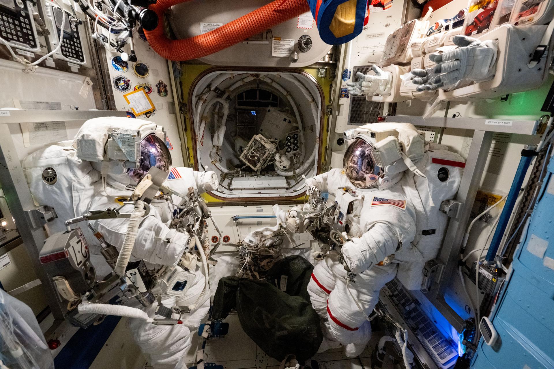 Two spacesuits are pictured staged inside the International Space Station's Quest airlock ahead of a spacewalk planned for NASA astronauts Suni Williams and Butch Wilmore. The two spacewalkers are scheduled to exit the Quest airlock on Jan. 30 to remove a radio frequency group antenna assembly and search for microbes outside the orbital outpost.