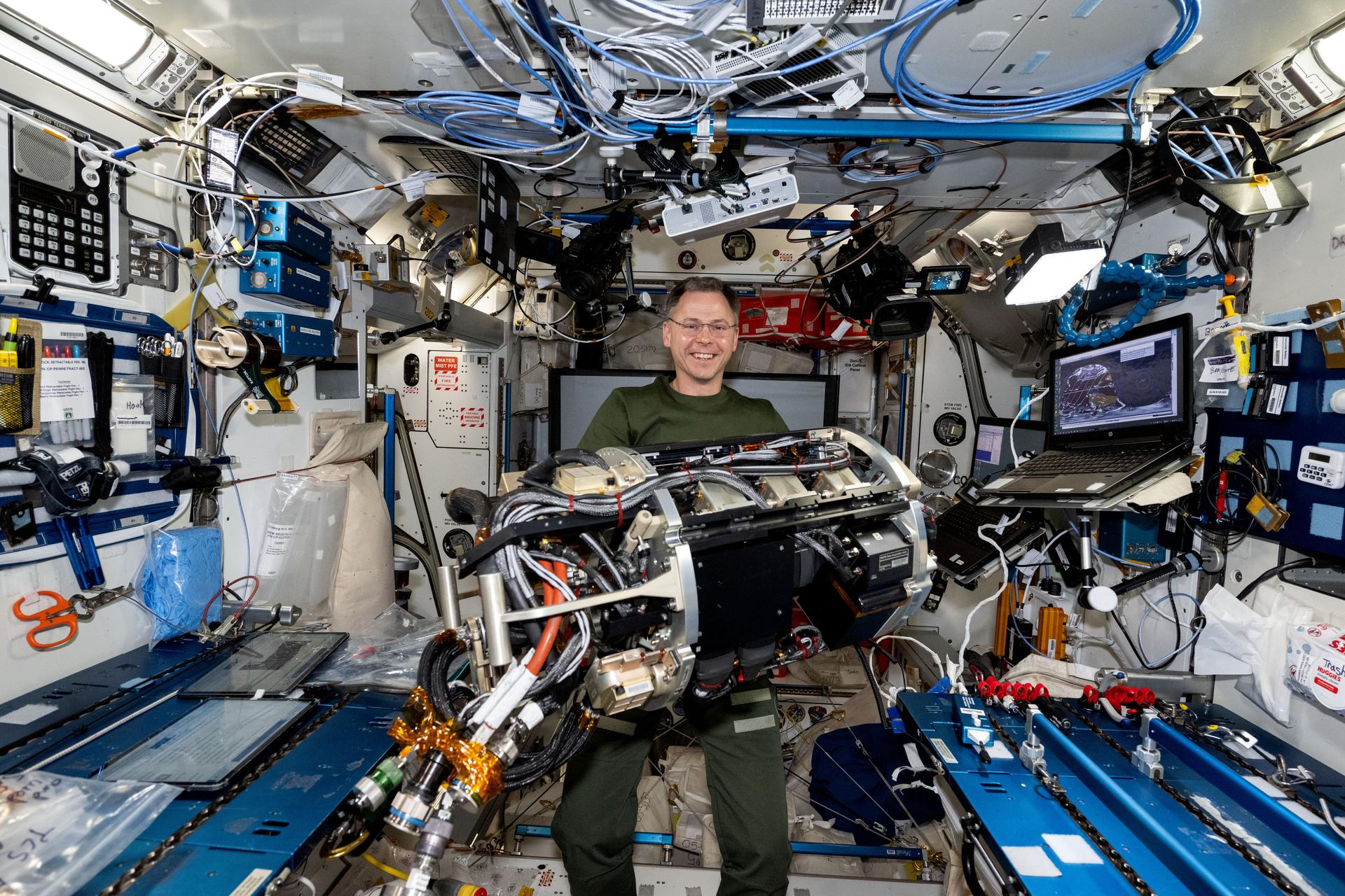 NASA astronaut and Expedition 72 Flight Engineer Nick Hague handles research hardware that is part of the Combustion Integrated Rack that enables safe fuel and flame research aboard the International Space Station.