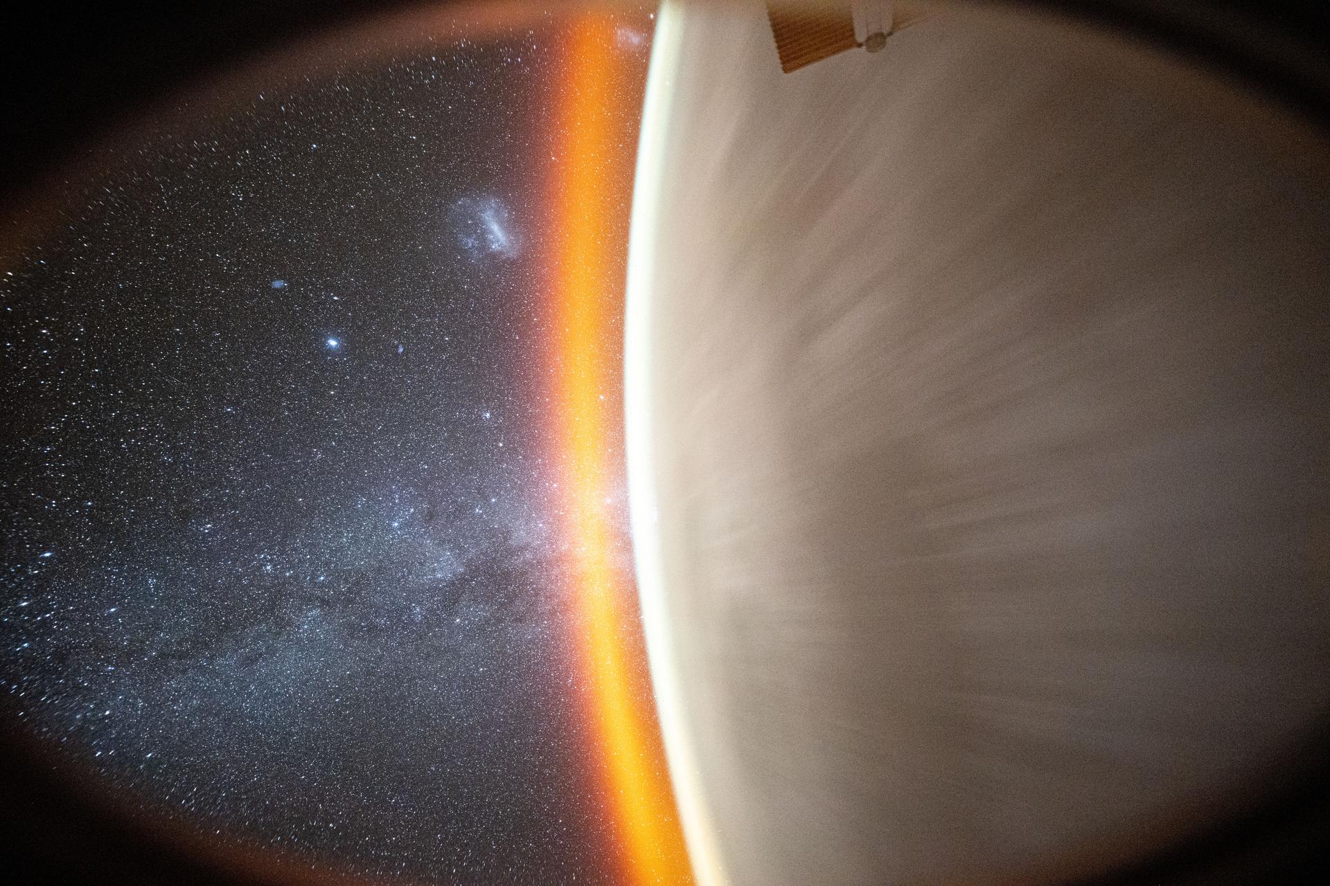 This celestial image captured by NASA astronaut Don Pettit using a camera with low light and long duration settings pointed out a window on the SpaceX Dragon crew spacecraft shows the Milky Way beyond Earth's horizon crowned by an atmospheric glow. The Large and Small Magellanic Clouds are also distinguishable as the International Space Station orbited 257 miles above the Pacific Ocean just east of Hawaii.