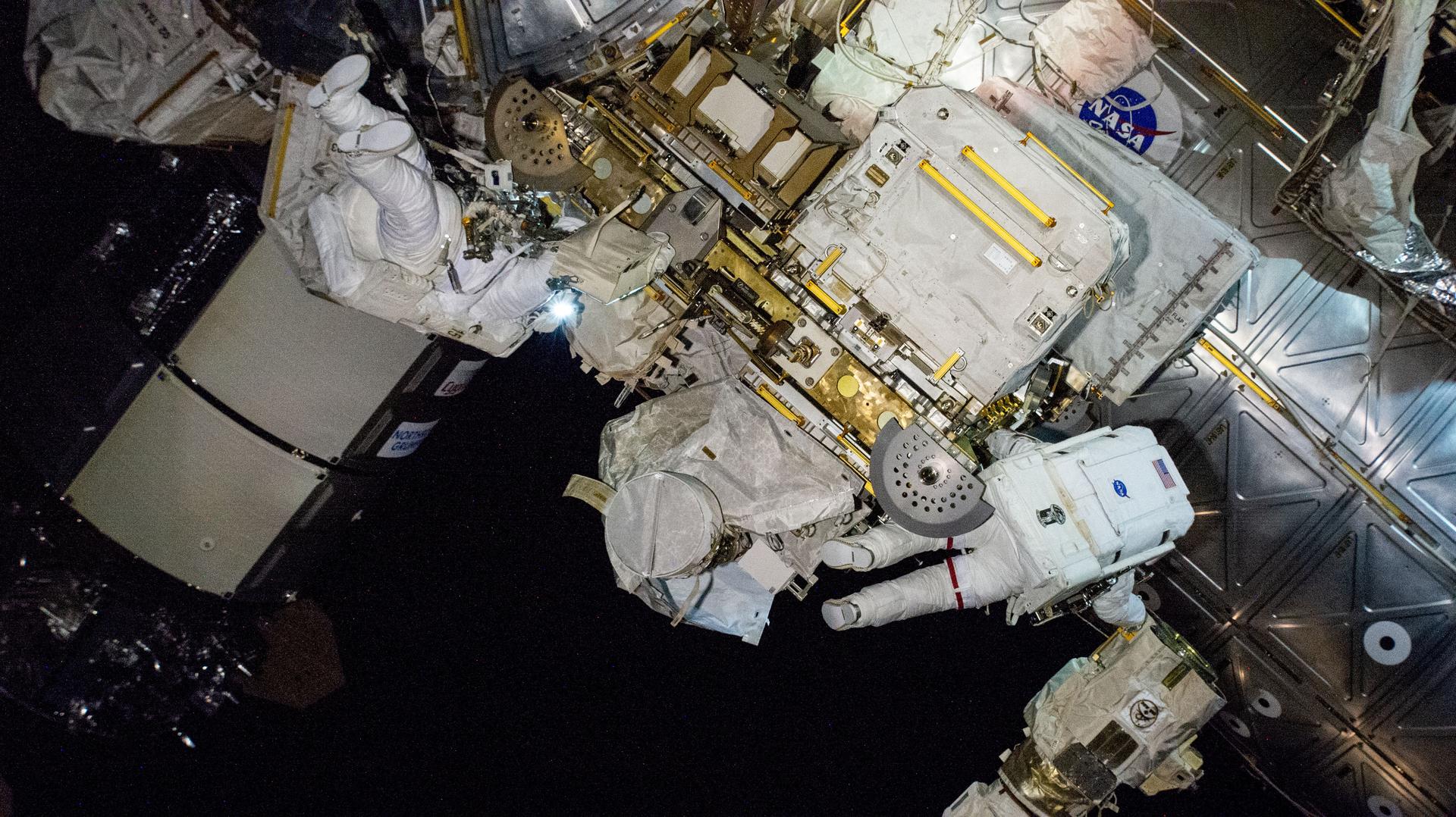 Two spacewalkers, Expedition 72 Flight Engineer Butch Wilmore (upper left) and Expedition 72 Commander Suni Williams (lower right), both NASA astronauts, work outside the International Space Station during a five-hour and 26-minute spacewalk to remove radio communciations hardware and swab for microorganisms.
