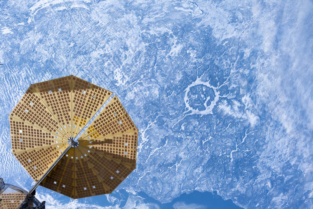 iss072e597522 (Jan. 31, 2025) --- An UltraFex solar array, one of two cymbal-shaped solar arrays on the Northrop Grumman Cygnus space freighter, is pictured in the foreground as the International Space Station orbited 261 miles above the 214 million-year-old Manicouagan crater in Quebec, Canada.