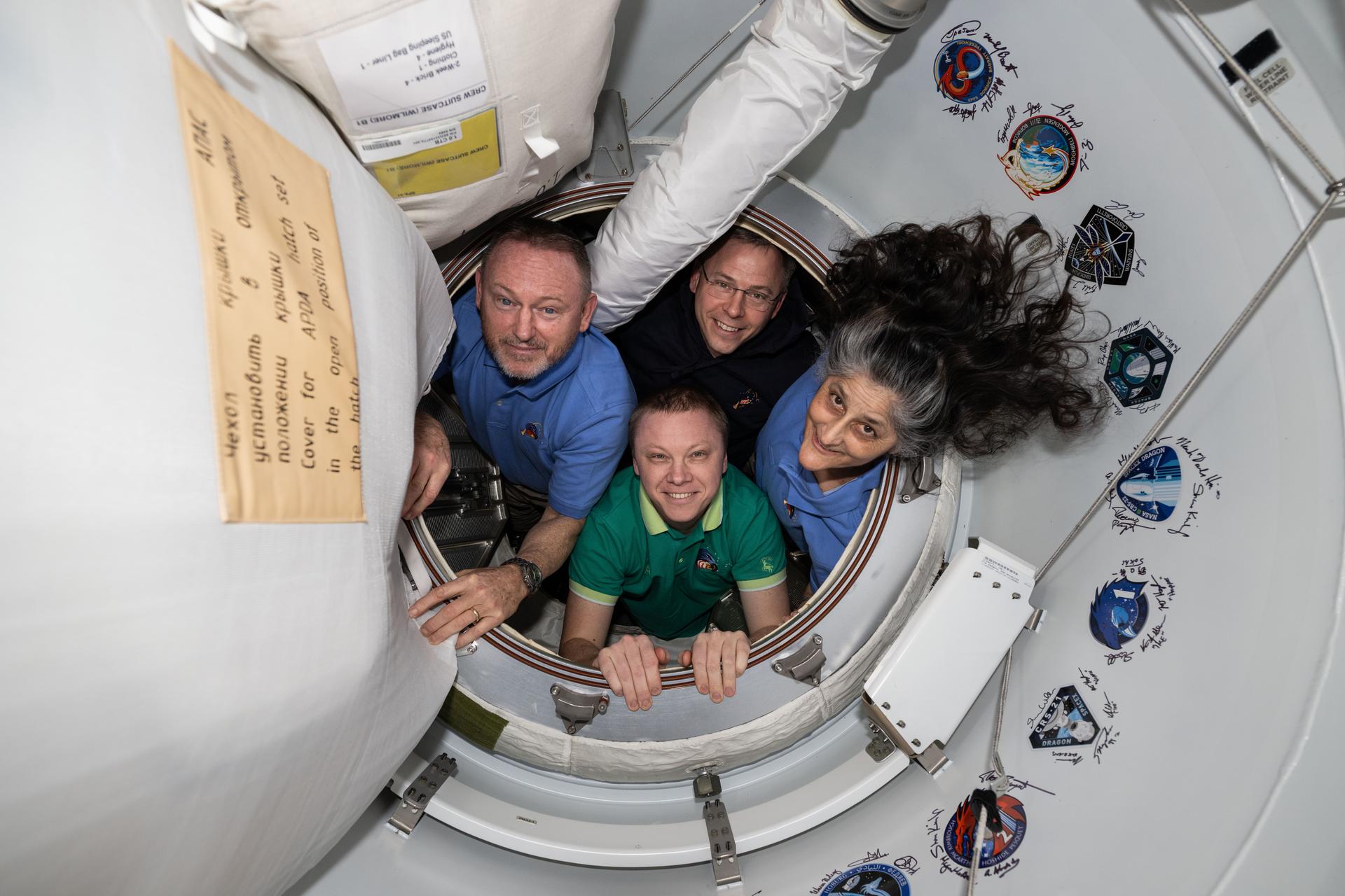 Các thành viên SpaceX Crew-9 của NASA tạo dáng chụp ảnh chân dung bên trong tiền sảnh giữa Trạm vũ trụ quốc tế và tàu vũ trụ SpaceX Dragon. Theo chiều kim đồng hồ từ trái sang là các phi hành gia NASA Butch Wimore, Nick Hague và Suni Williams, và phi hành gia Roscosmos Aleksandr Gorbunov.