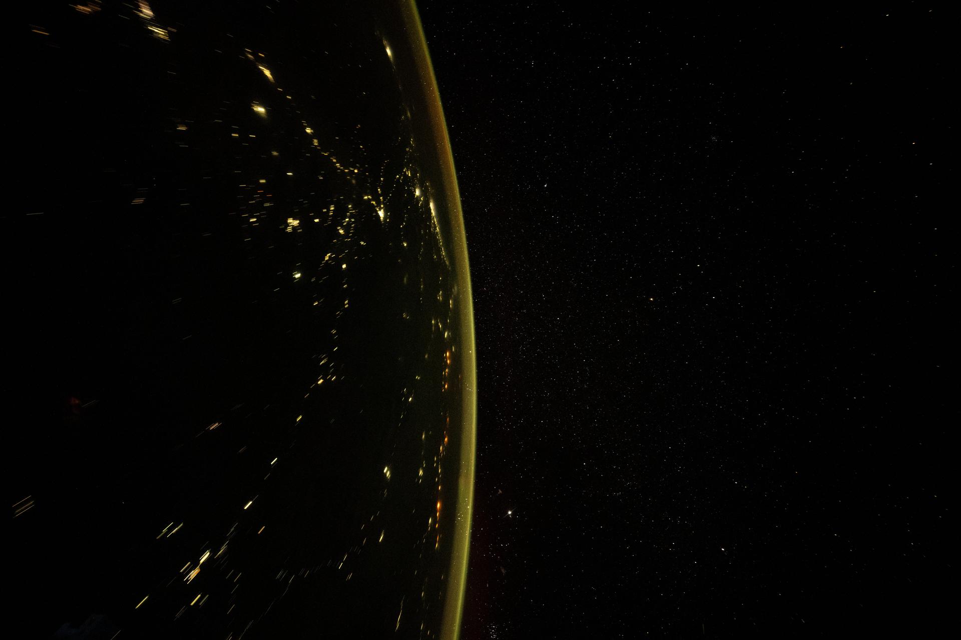City lights dot the Asian continent with an atmospheric glow blanketing Earth's horizon underneath a starry sky in this long-duration photograph from the International Space Station as it orbited 265 miles above.