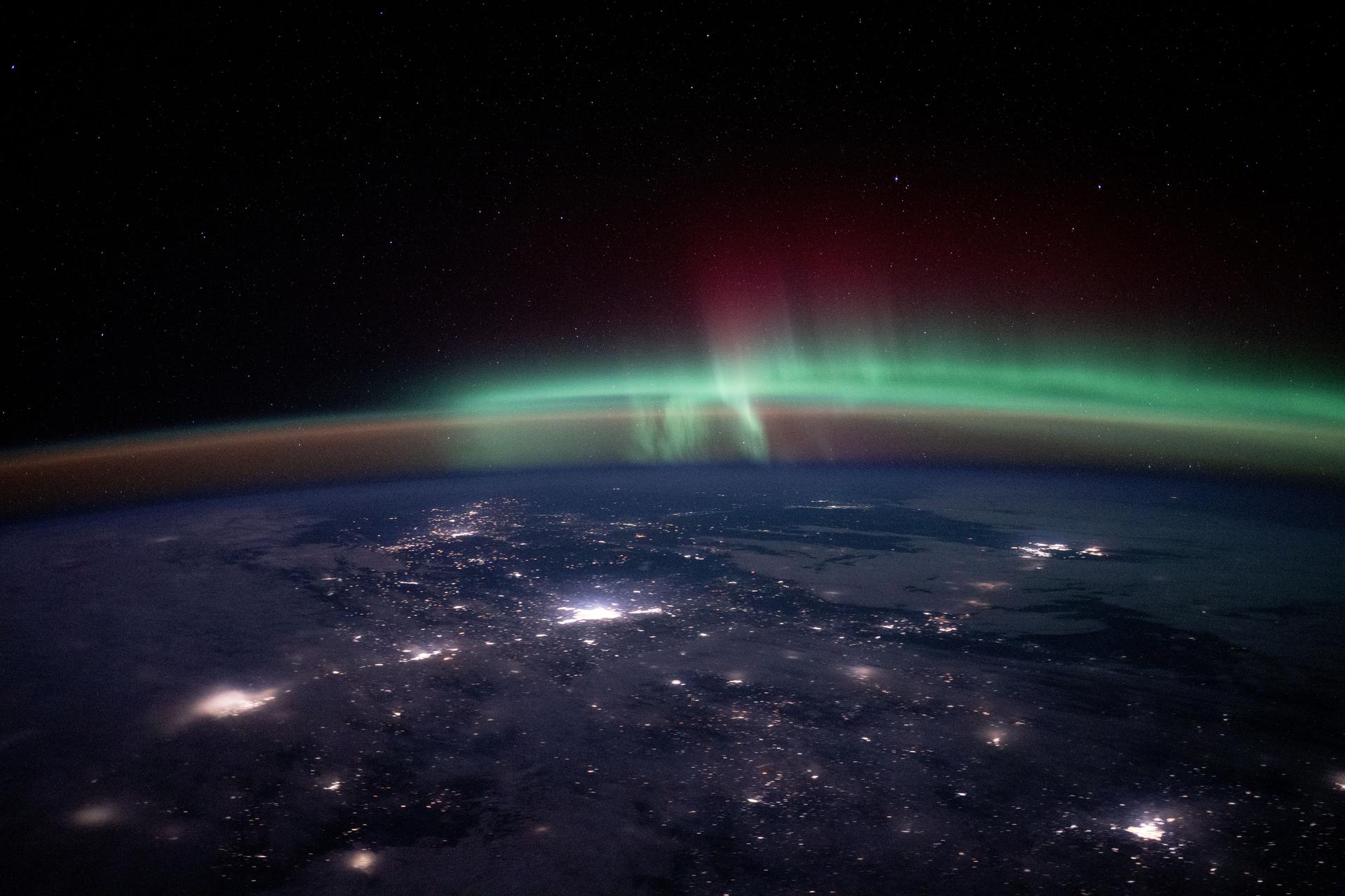 City lights dot the Canadian landscape underneath an atmospheric glow and an aurora borealis in this photograph taken from the International Space Station 262 miles above North America at approximately 12:15 a.m. local time.