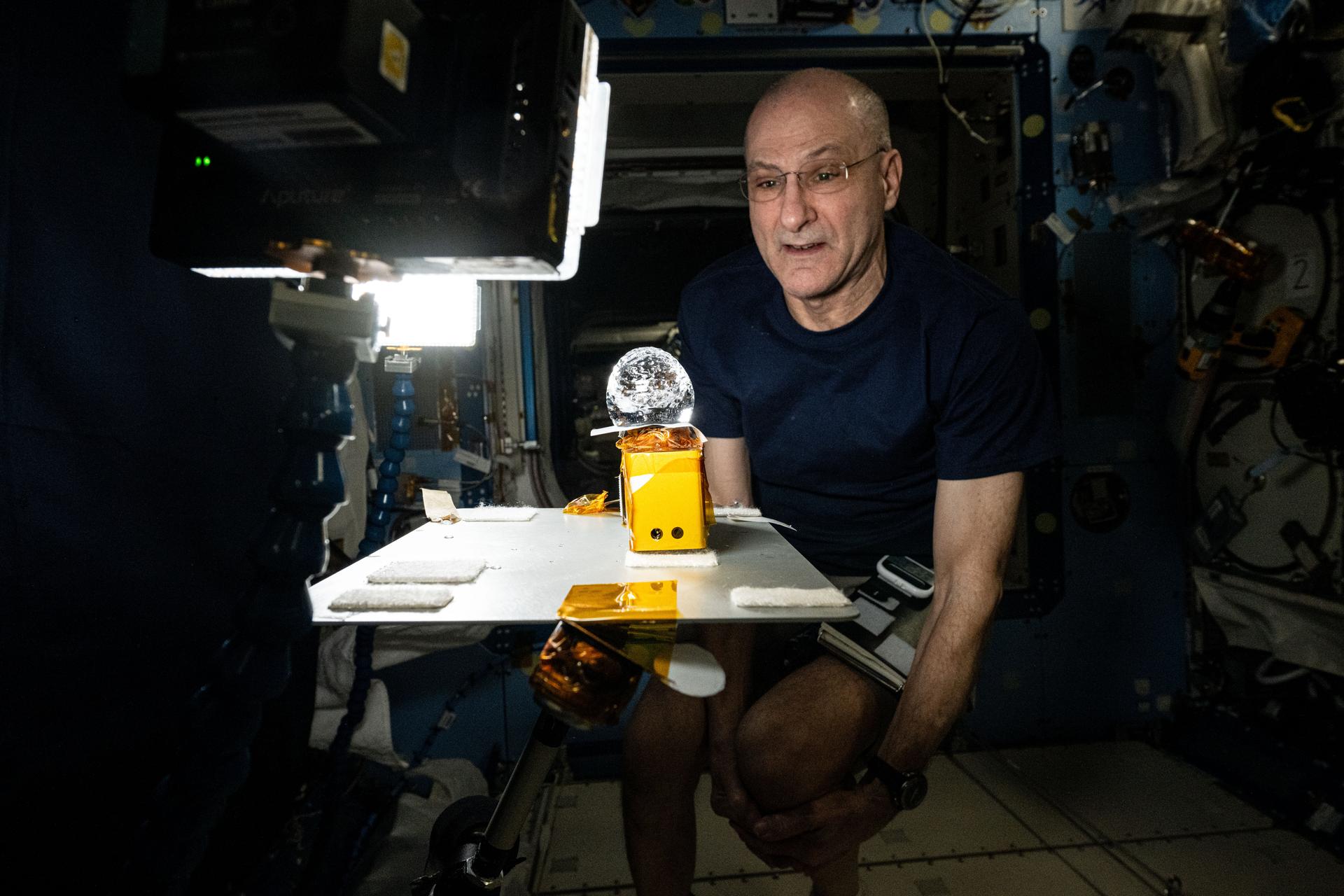 NASA astronaut and Expedition 72 Flight Engineer Don Pettit stares at a ball of water shaped by microgravity and attached to research hardware by surface tension. Pettit was demonstrating simple space physics phenomena inside the International Space Station's Kibo laboratory module.