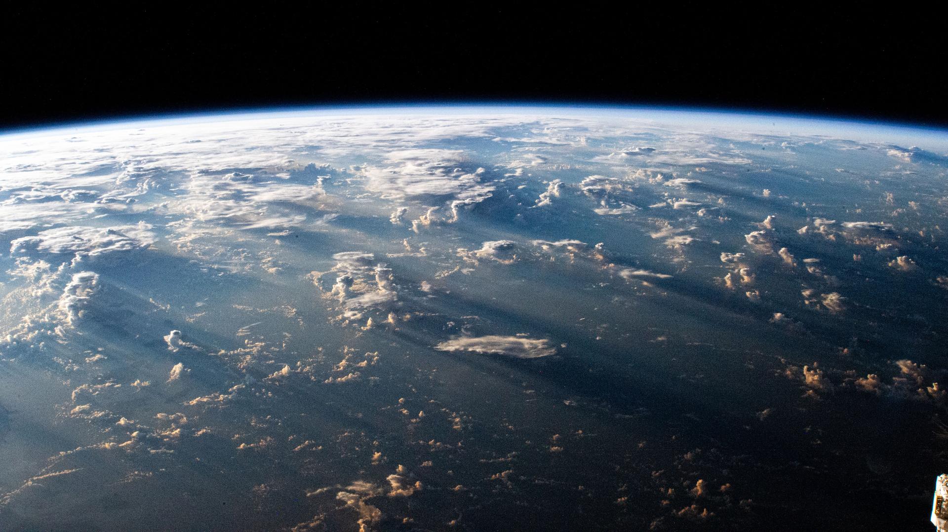 A Southeast Asian sunrise casts long shadows behind clouds in this photograph from the International Space Station as it orbited 263 miles above the Bismarck Sea.