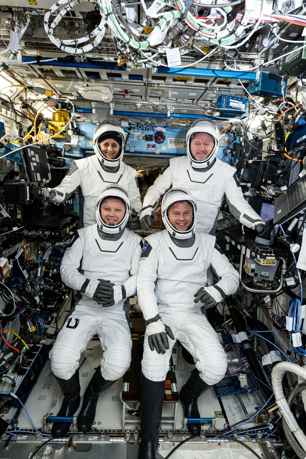 The four SpaceX Crew-9 members are suited up in their Dragon pressure suits testing them for a fit check one week before their departure aboard the Dragon crew spacecraft. Clockwise from top left are, NASA astronauts Suni Williams, Butch Wilmore, and Nick Hague, and Roscosmos cosmonaut Aleksandr Gorbunov. The Commercial Crew quartet is pictured inside the International Space Station's Destiny laboratory module.