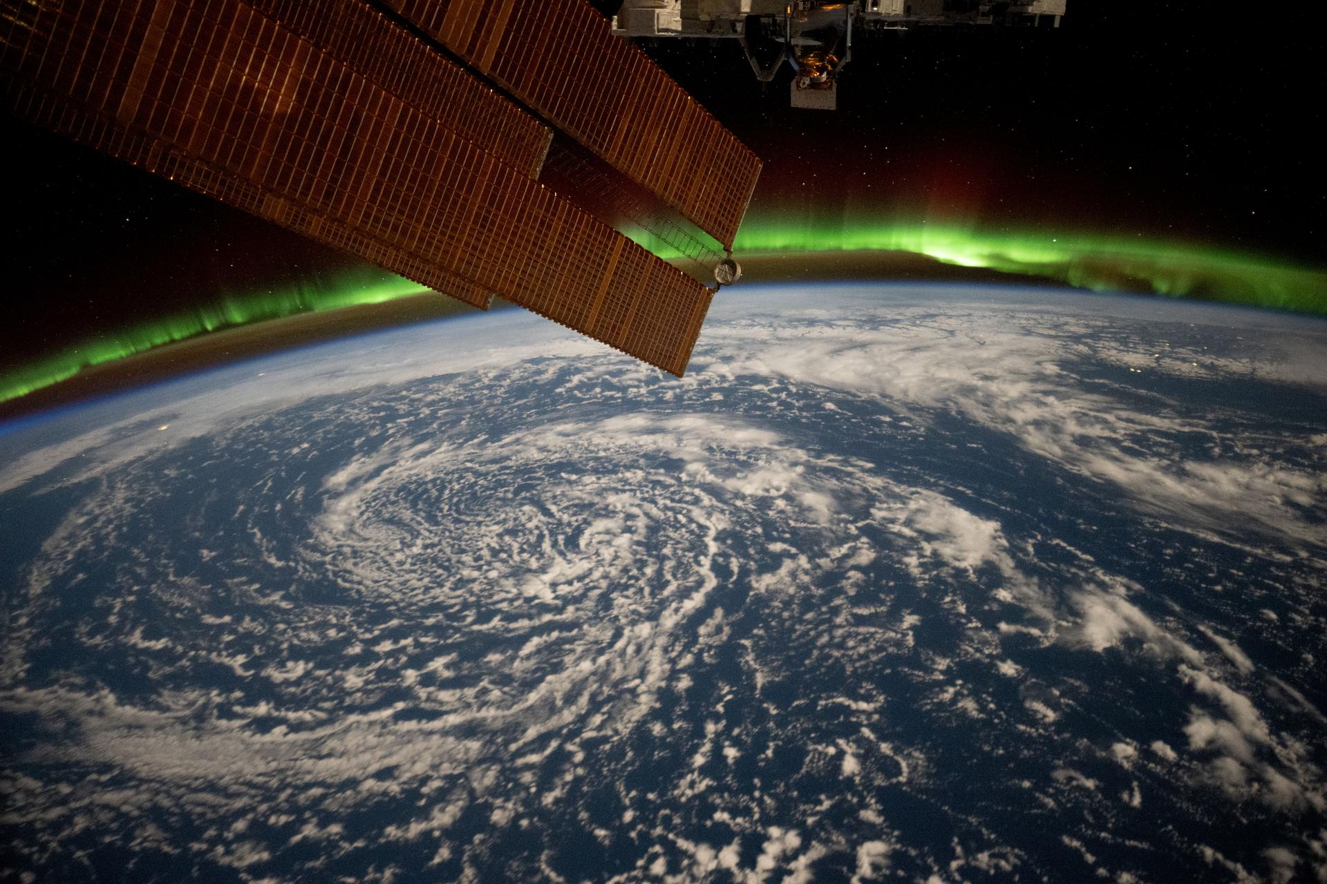 Clouds swirl over the Gulf of Alaska and underneath the aurora borealis blanketing Earth's horizon in this photograph from the International Space Station as it orbited 261 miles above.