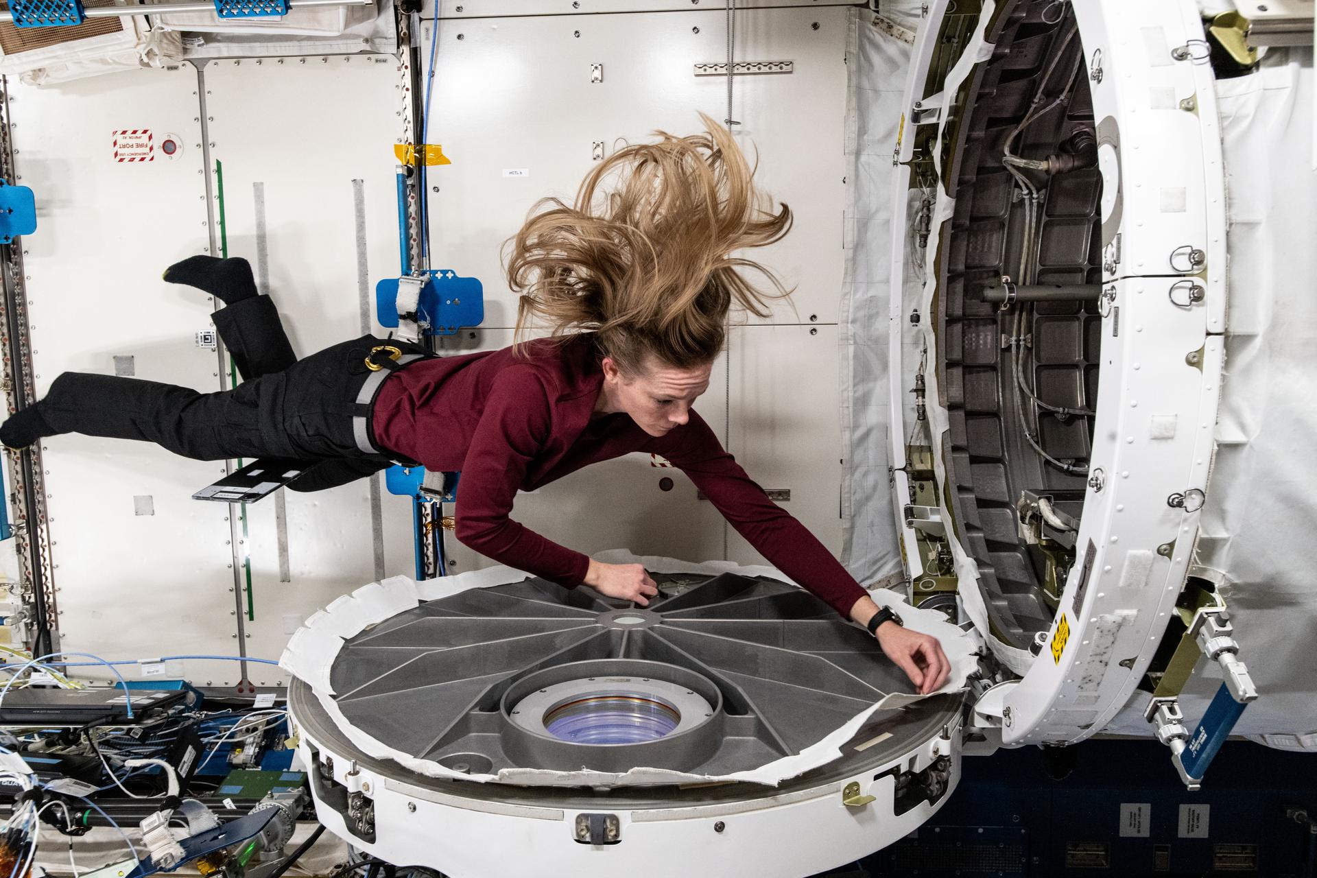 NASA astronaut and Expedition 72 Flight Engineer Nichole Ayers opens the hatch to the Kibo laboratory module's airlock aboard the International Space Station.