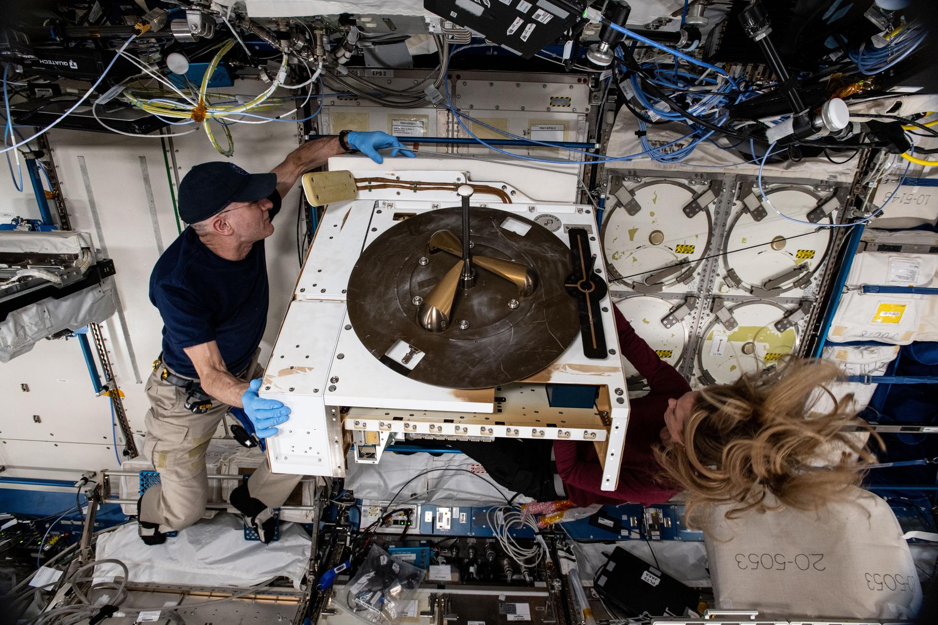 NASA astronauts Don Pettit and Nichole Ayers, both Expedition 72 Flight Engineers, prepare the NanoRacks External Platform with its grapple fixture attached for stowage aboard the International Space Station's Kibo laboratory module. The commercial research platform housed three different electrical and optical experiments that tested operations while exposed to the vacuum of space.