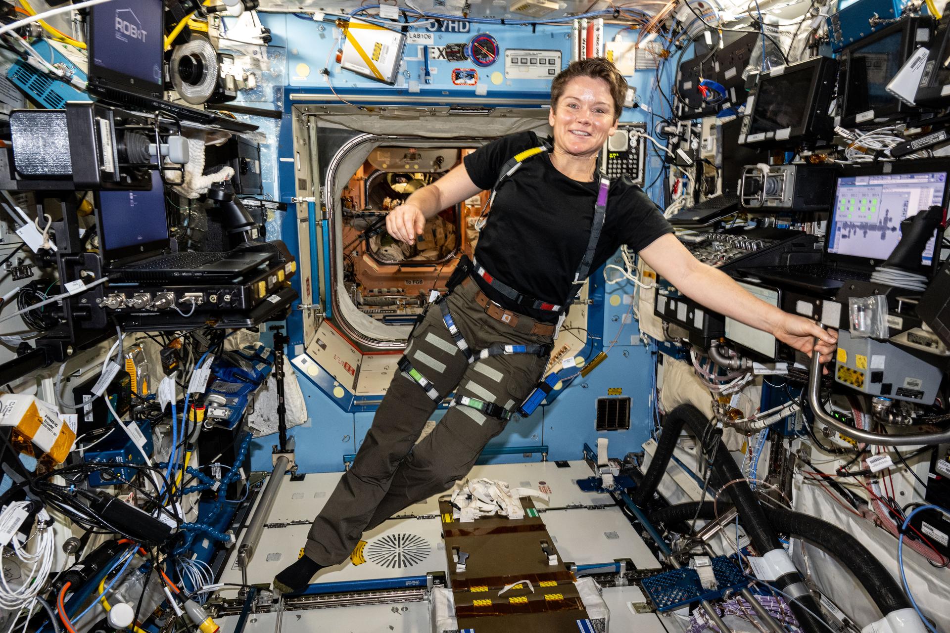 NASA astronaut and Expedition 72 Flight Engineer Anne McClain is pictured in the Destiny laboratory module wearing an experimental wearable dosimeter that measures radiation dosages crews are exposed to in real time aboard the International Space Station.