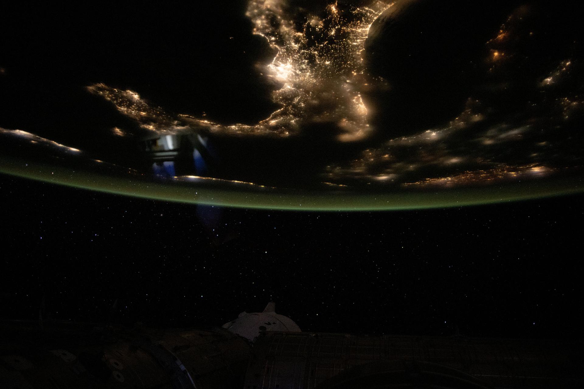 The boot of Italy well-defined by the nation's city lights stands in contrast to the Tyrrhenian Sea (left) and the Adriatic Sea (right) with the Balkans at far right underneath an atmospheric glow blanketing Earth's horizon. The International Space Station was orbiting 262 miles above southern Europe at 10:57 p.m. local time when this photograph was taken.