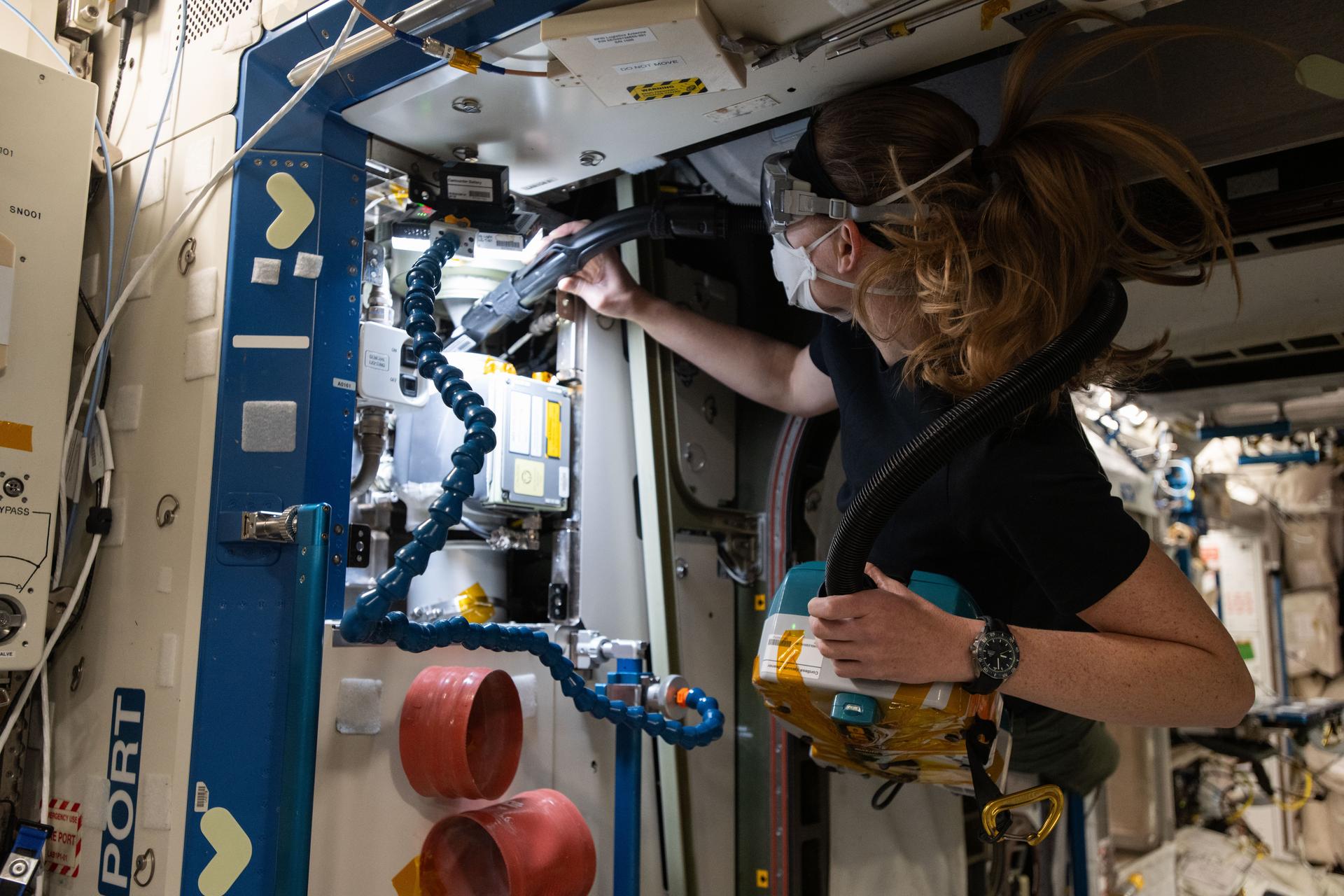 NASA astronaut and Expedition 72 Flight Engineer Nichole Ayers cleans ventilation system fans and inlets inside the International Space Station's Destiny labortory module.