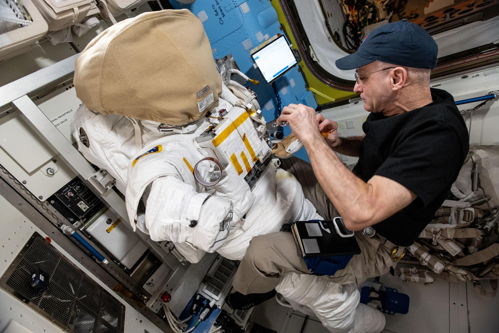 NASA astronaut and Expedition 72 Flight Engineer Don Pettit inspects a spacesuit aboard the International Space Station's Quest airlock.