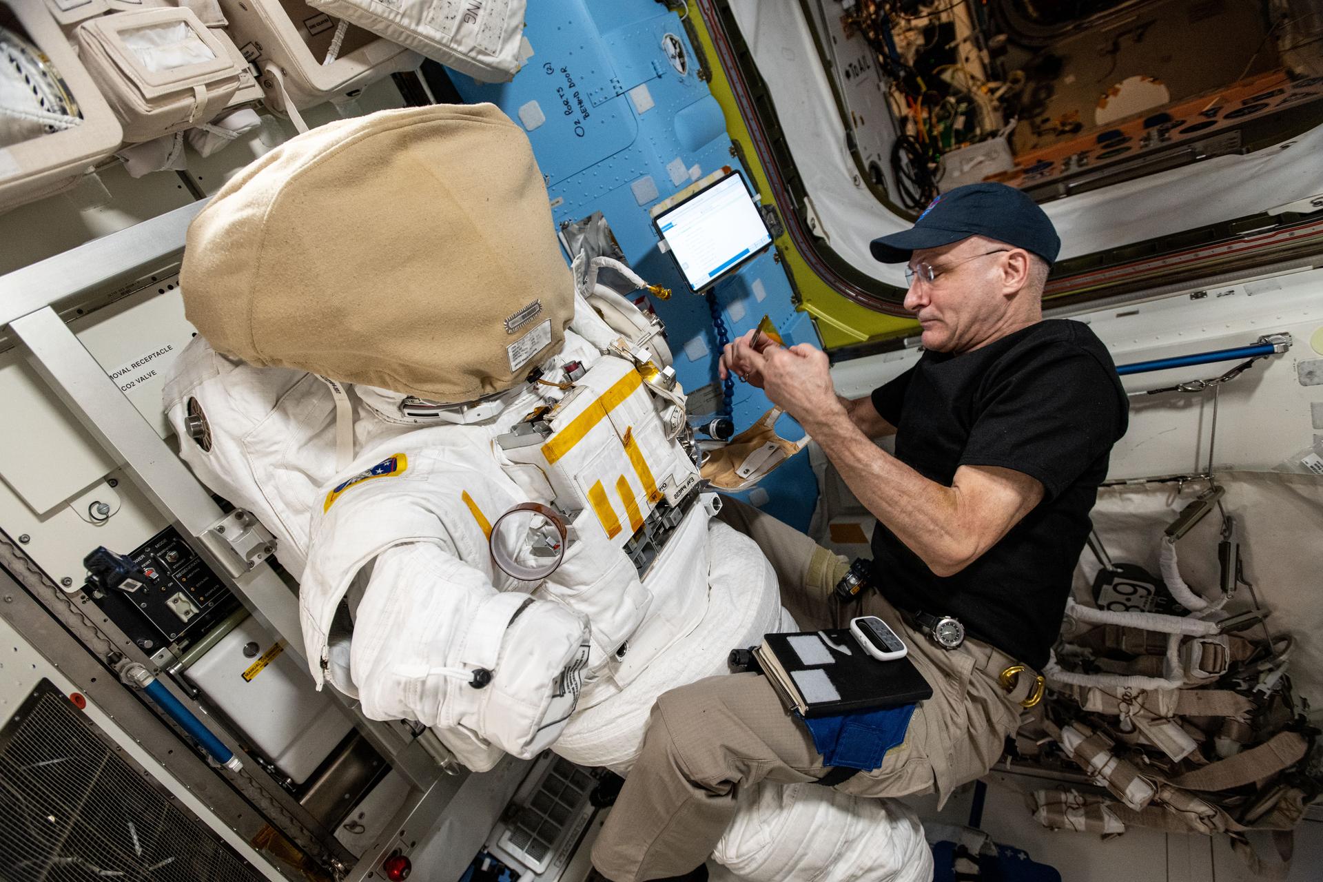 NASA astronaut and Expedition 72 Flight Engineer Don Pettit inspects a spacesuit aboard the International Space Station's Quest airlock.