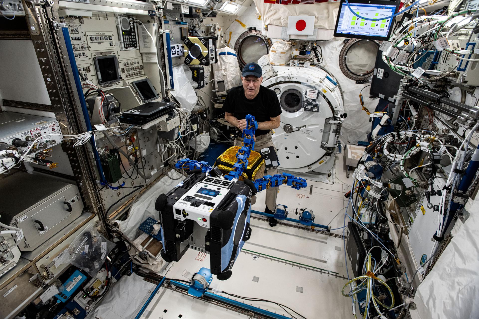 NASA astronaut and Expedition 72 Flight Engineer Don Pettit watches as an Astrobee robotic free-flyer outfitted with tentacle-like grippers grapples a "capture cube" inside the International Space Station's Kibo laboratory module.
