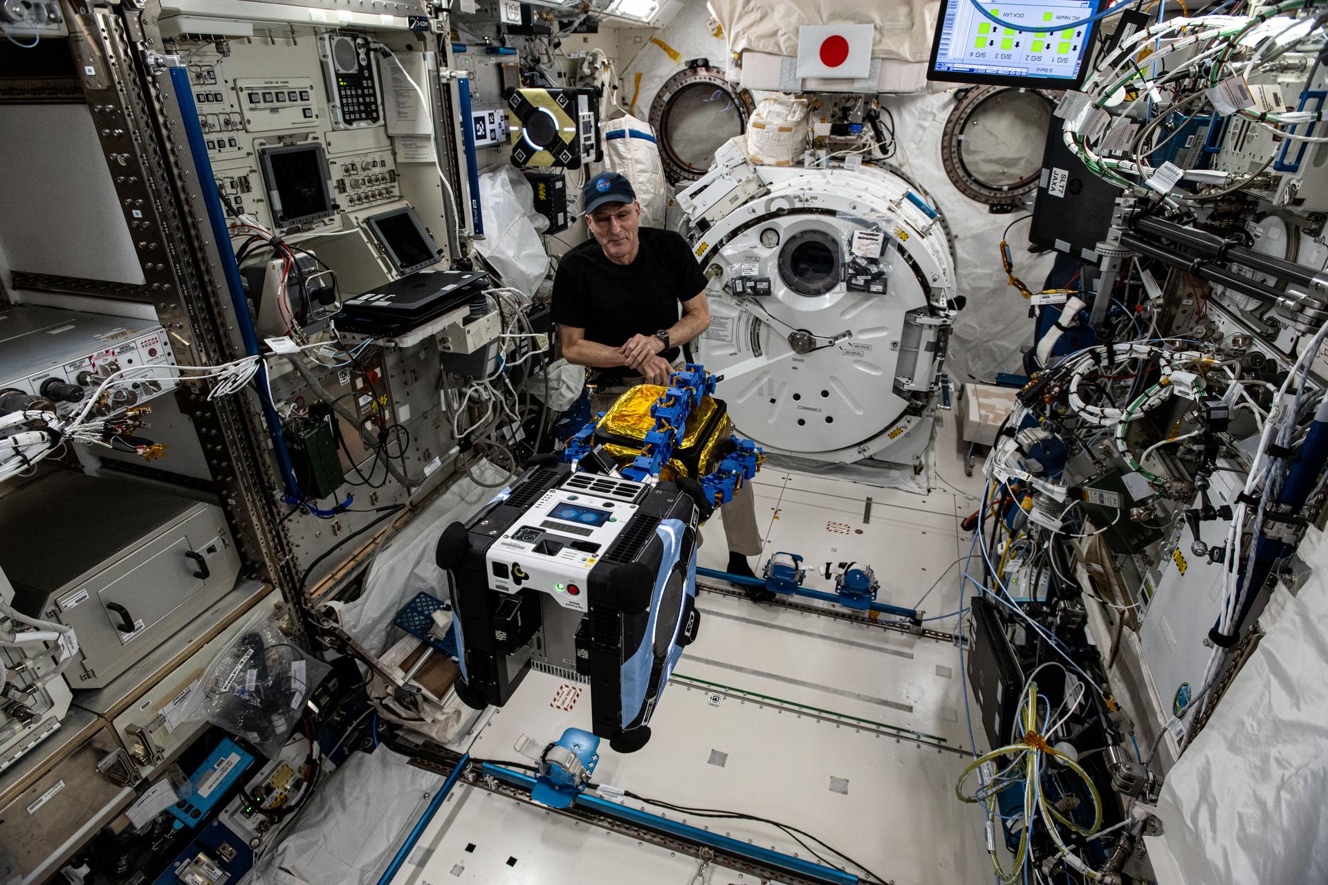NASA astronaut and Expedition 72 Flight Engineer Don Pettit watches as an Astrobee robotic free-flyer outfitted with tentacle-like grippers grapples a "capture cube" inside the International Space Station's Kibo laboratory module.